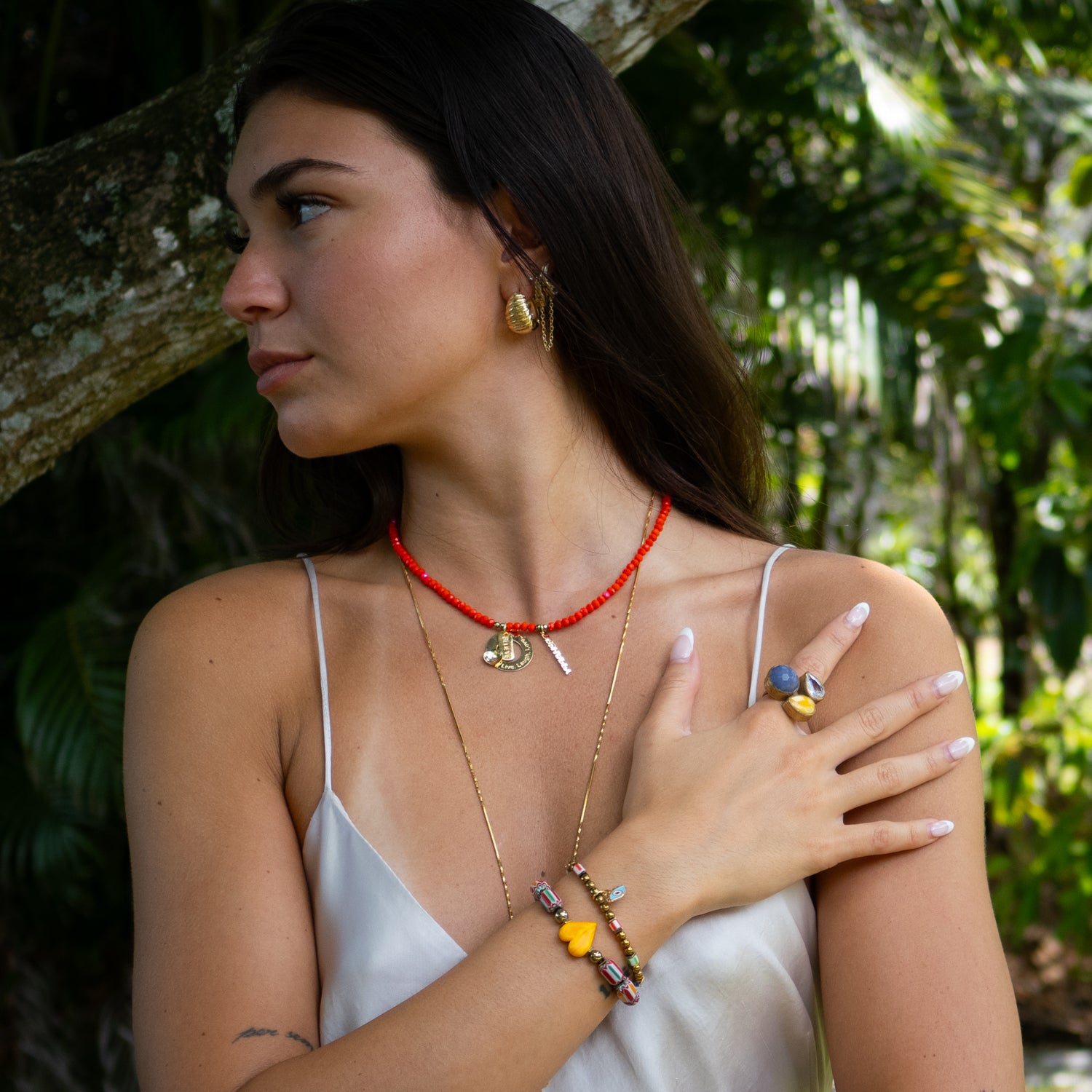 Close-up of gold “Live, Laugh, Love” charm and “Be Happy” tag on vibrant crystal choker.

