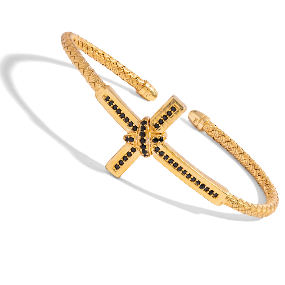 Angled view of the woven gold cuff showing the black zircon cross, the wrapped X knot and the capped open ends