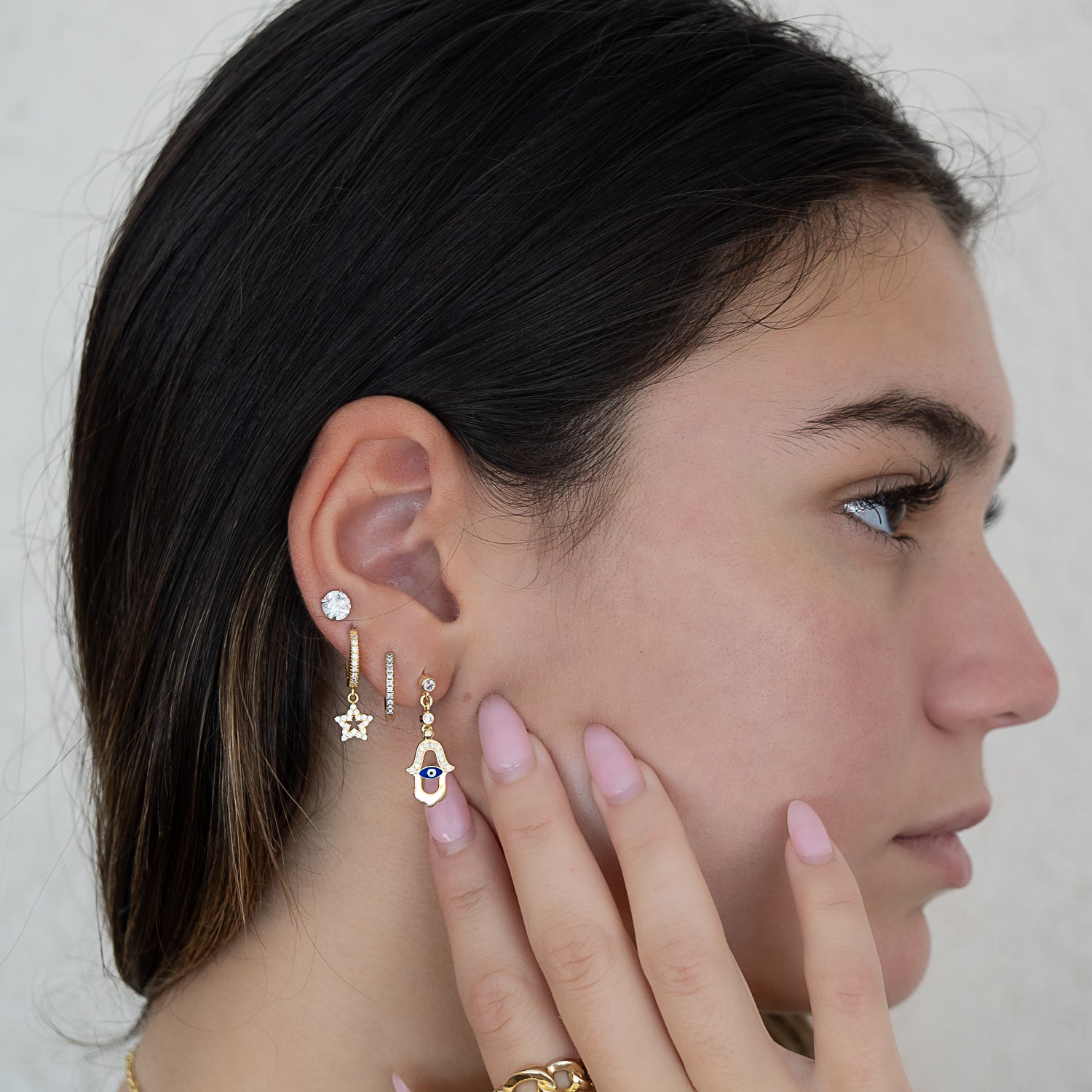 Model showcasing the Blue Evil Eye Gold Hamsa Earrings