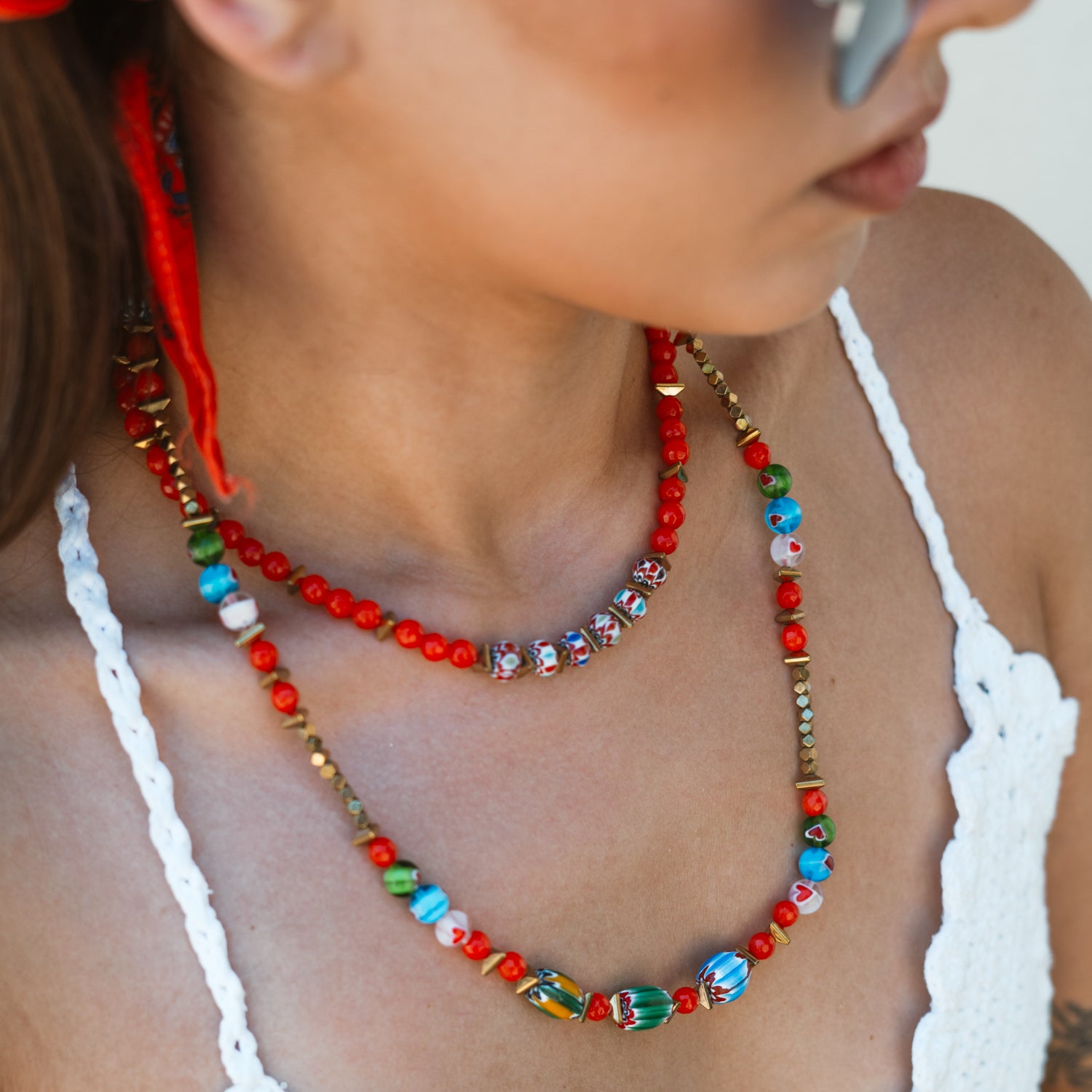 Close-up of the Carnelian Fire Energy Beaded Choker layered with a longer beaded necklace on model's neck, showing colorful African beads and carnelian