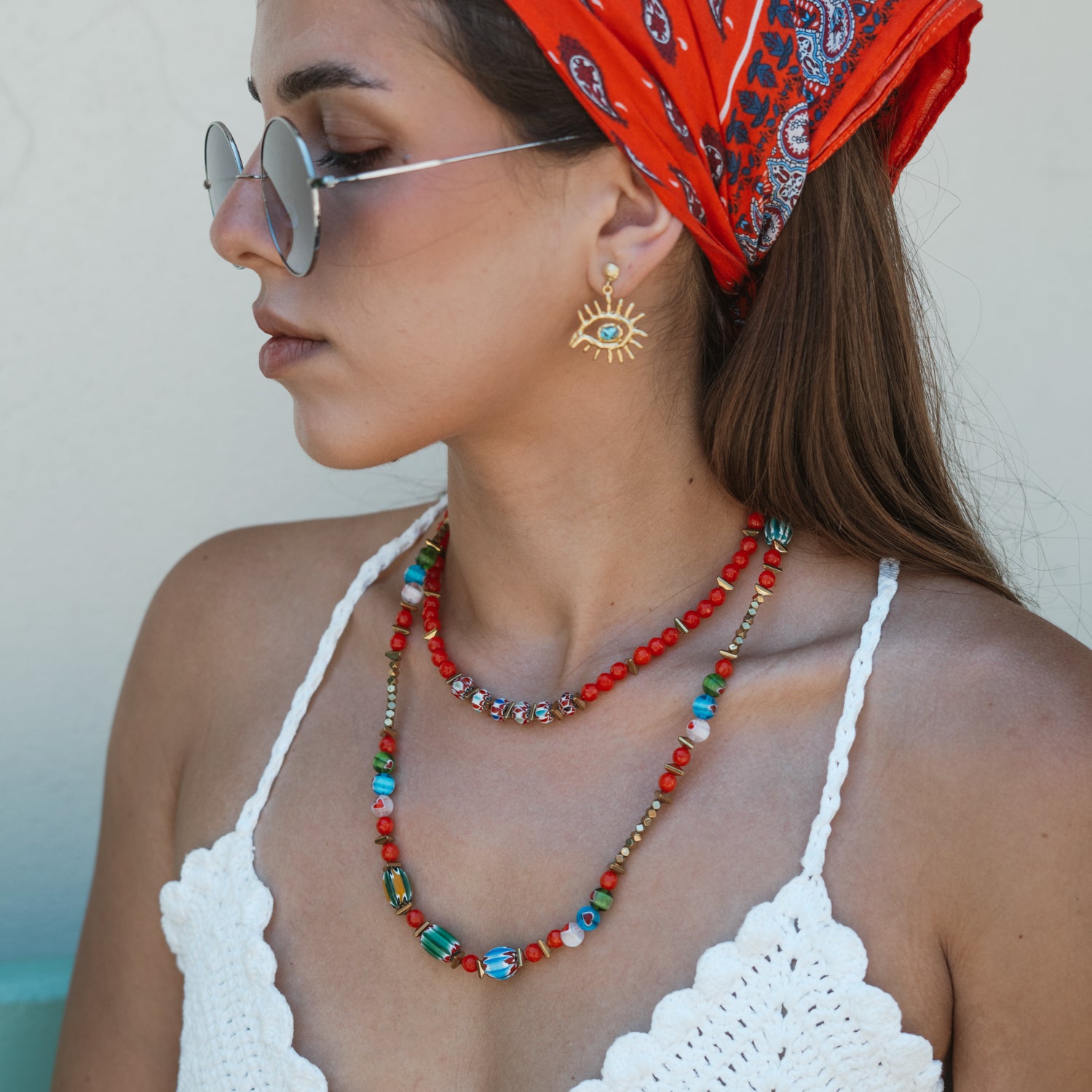 Model in a red paisley headscarf wearing the colorful Carnelian Rainbow Energy Beaded Necklace, a handmade boho beaded necklace layered with a gold necklace
