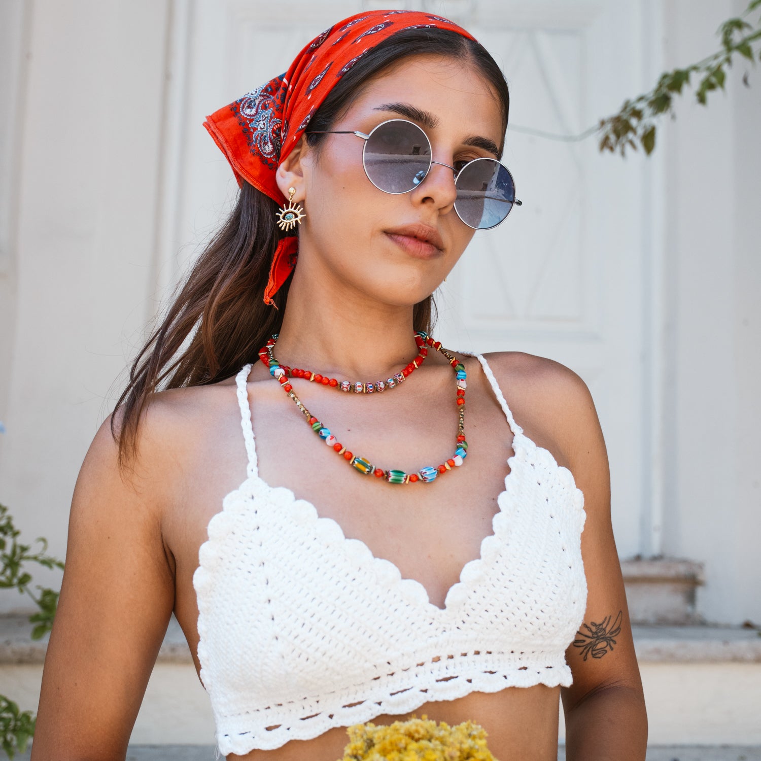 Model in a red headscarf wearing the colorful handmade Carnelian Rainbow Energy Beaded Necklace with a white crochet top, holding dried yellow flowers