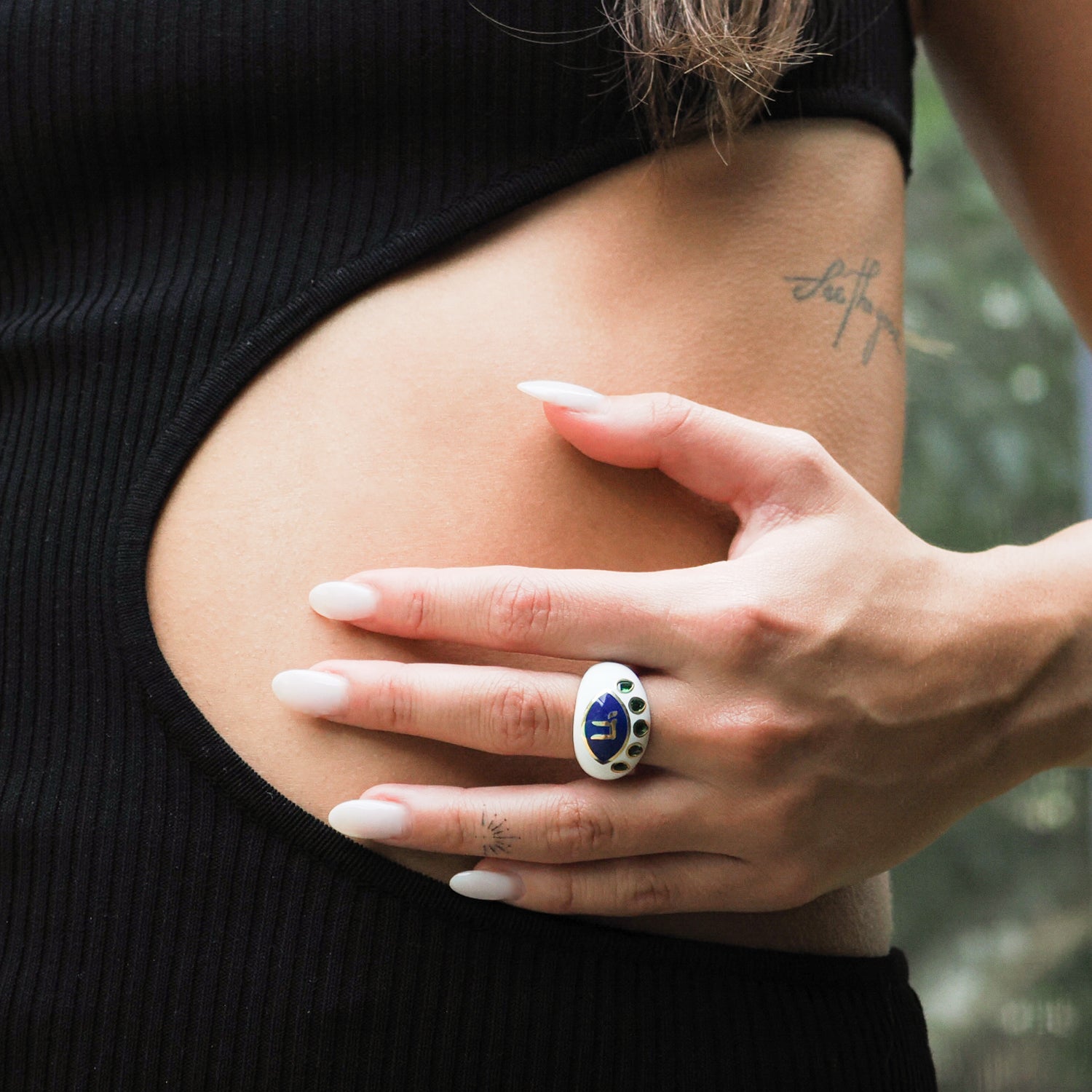 Elegant blue enamel ring featuring a protective eye design with a Chai symbol at the center, adorned with emerald stones.
