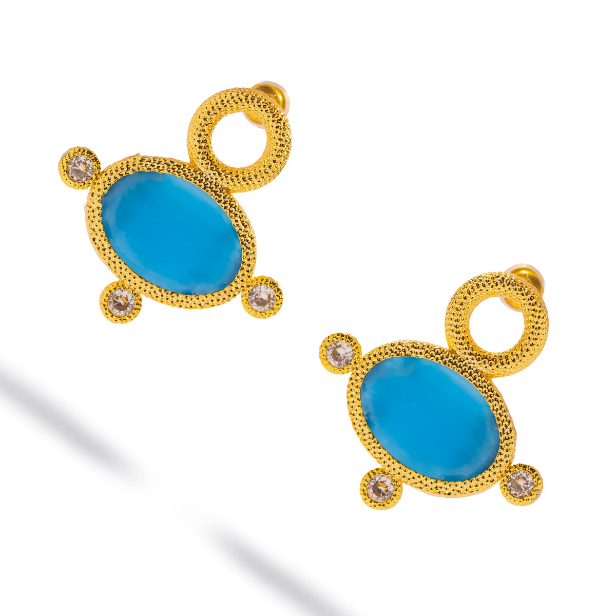 Angled view of the pair showing the granulated gold surface and the depth of the blue cat's eye stone