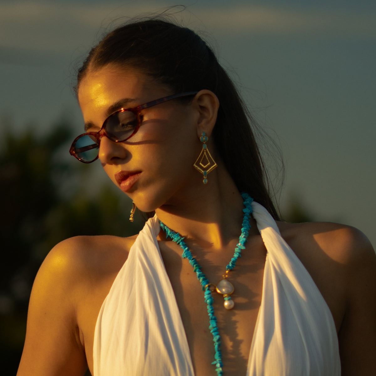 Turquoise and gold kite dangle earrings worn with a turquoise chip necklace at sunset