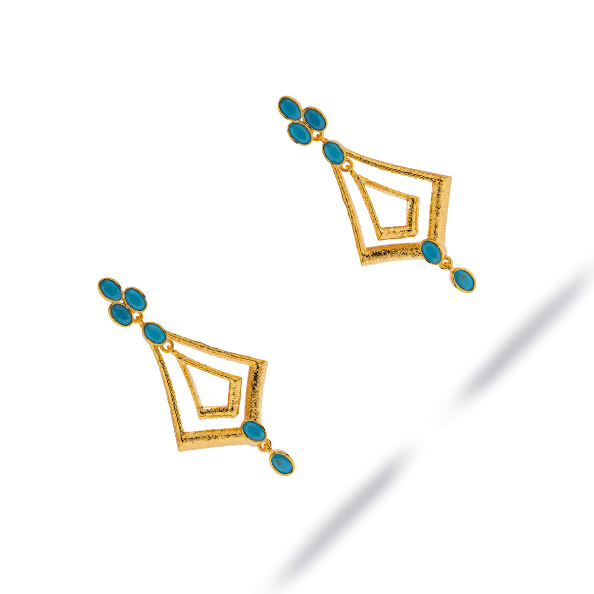 Pair of 24K gold plated brass dangle earrings with turquoise cabochons, angled view on white