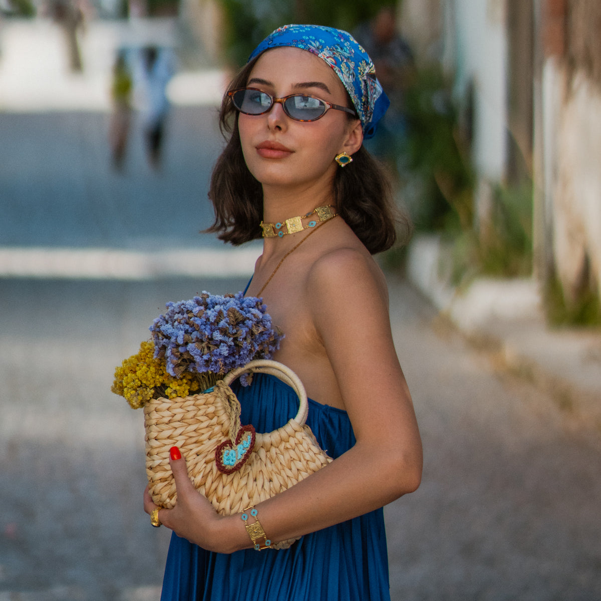 Model with a woven bag wearing the Cleopatra Evil Eye Turquoise &amp; Coral Engraved Gold Collar Necklace with the matching engraved gold bracelet