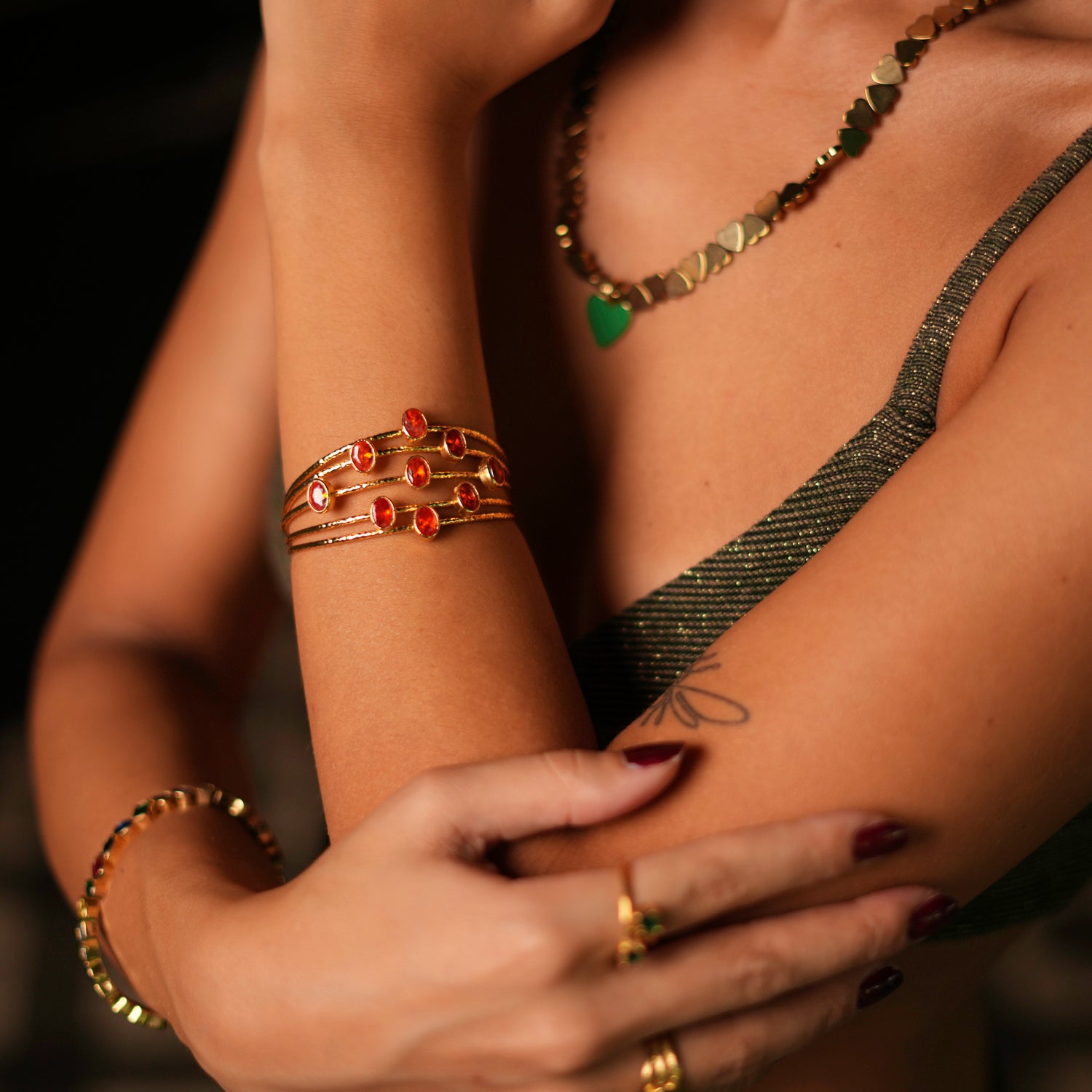 Elegant gold cuff bracelet with 24k plating, featuring five intertwined gold wires and oval carnelian stones, adjustable size.
