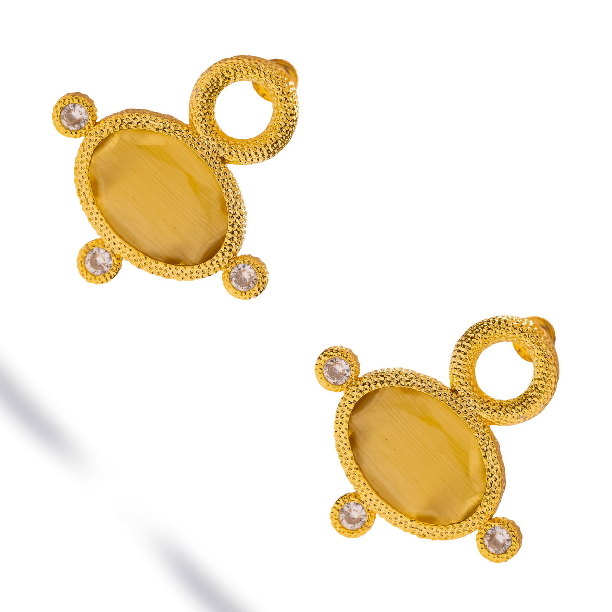 Cleopatra Golden Citrine Cat Eye Gold Statement Earrings laid diagonally on white, oval citrine-colored stones in textured gold
