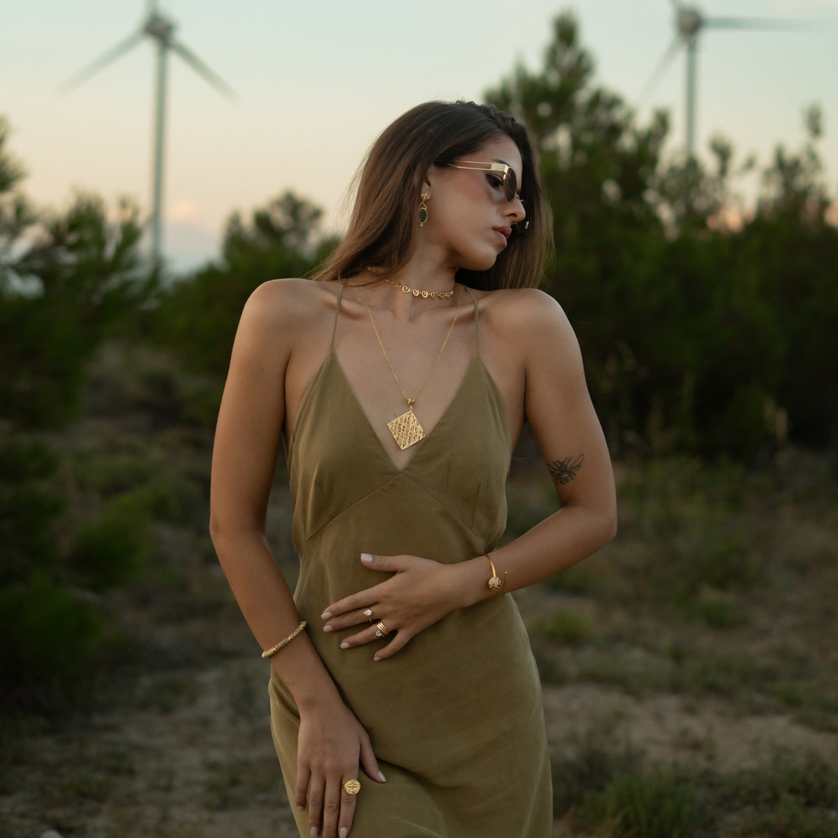 Model in an olive silk dress wearing the Cleopatra Golden Lace Long Pendant Necklace layered with a gold choker