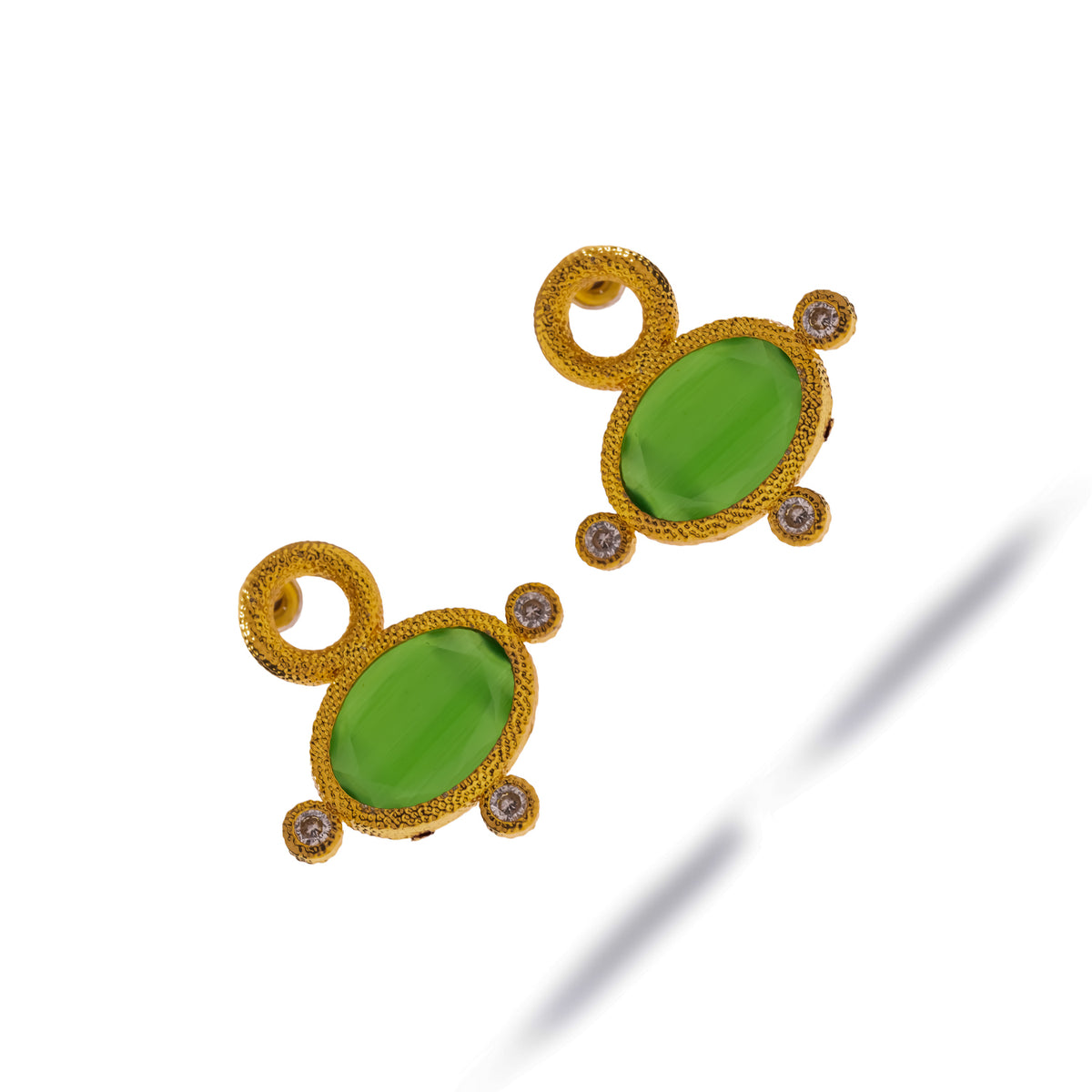 Cleopatra Green Cat Eye earrings laid diagonally, showing the open gold circle above each oval green stone