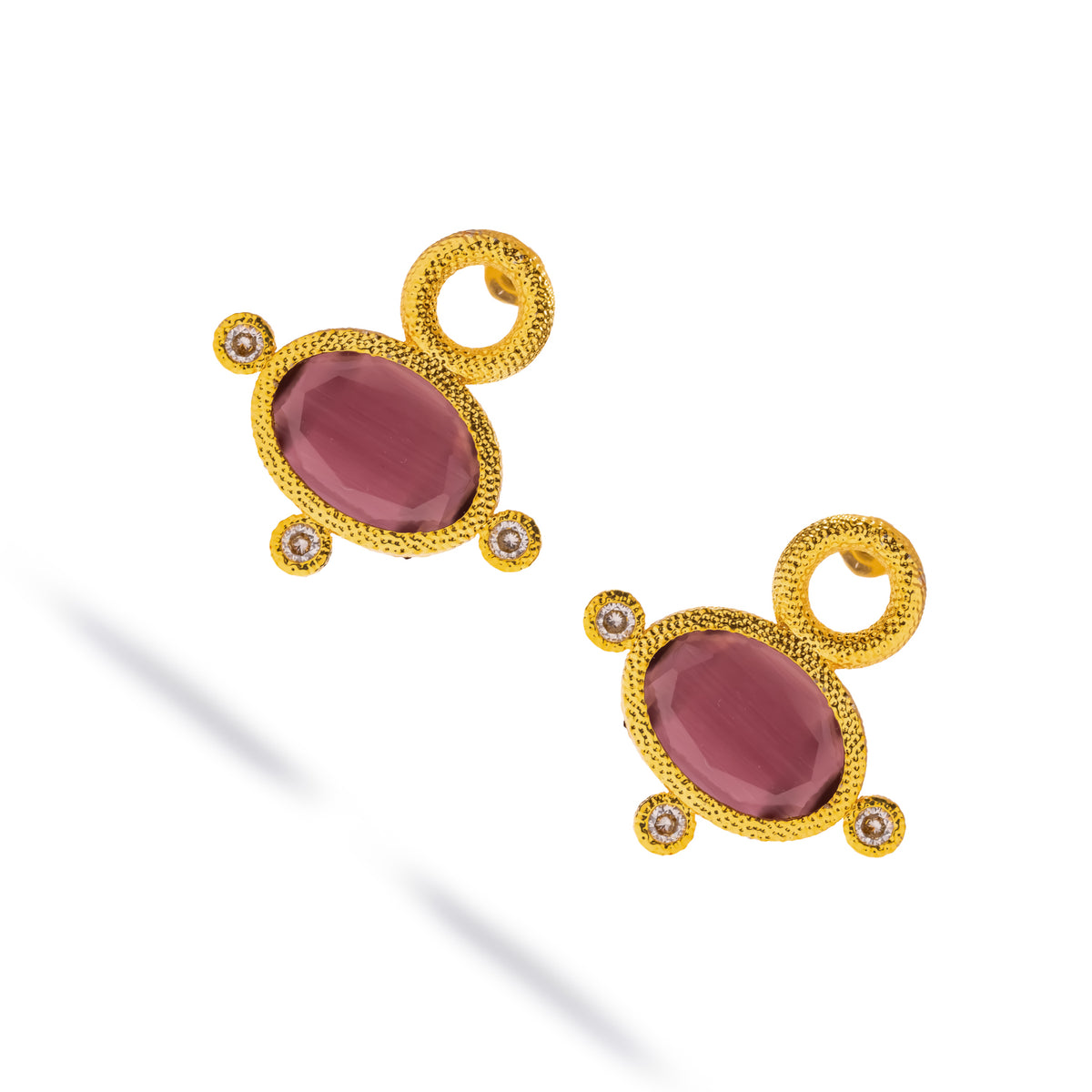 Pair of Cleopatra Mocha Cat Eye earrings at an angle, textured gold frames and three clear zircon accents