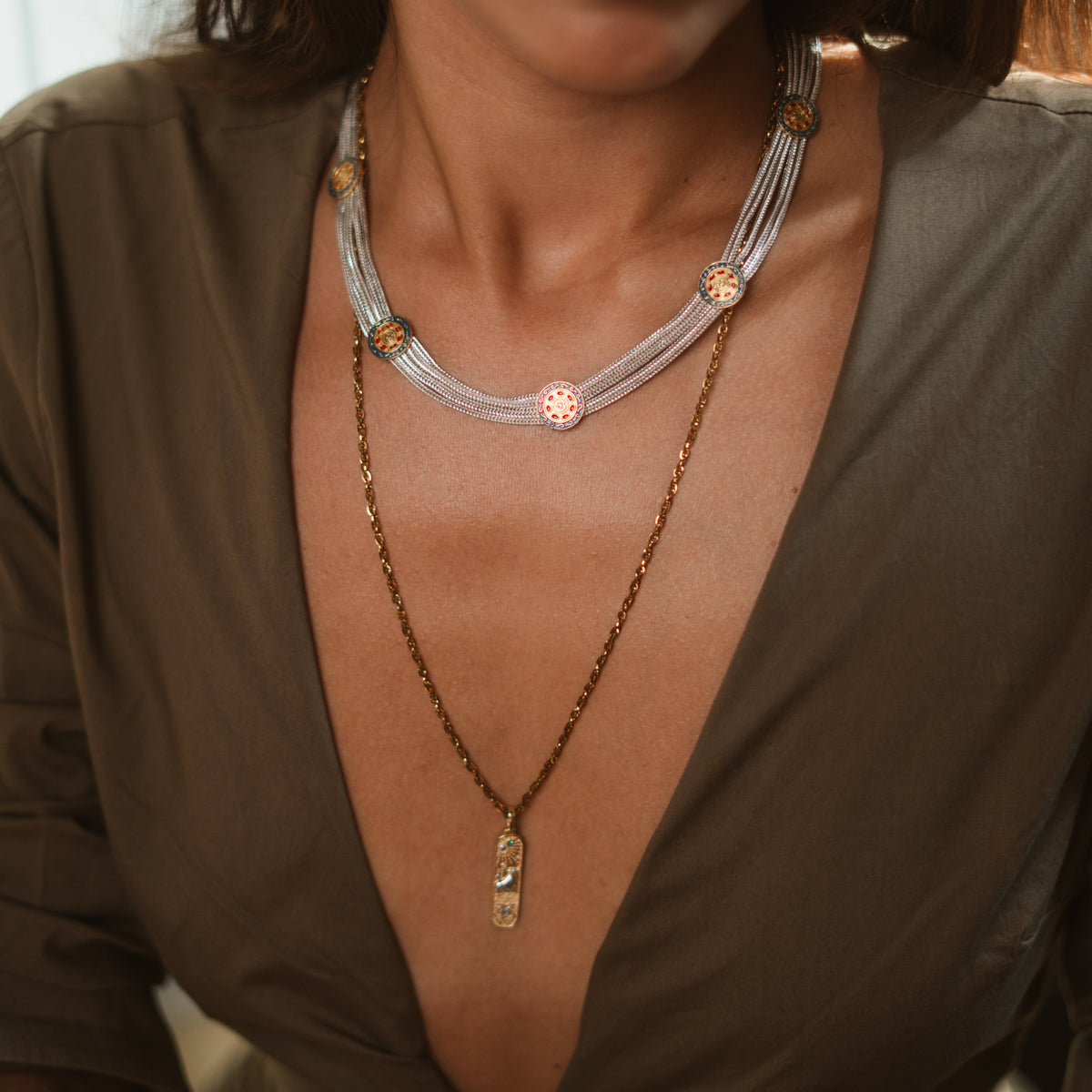 Model in an olive wrap top wearing the Cleopatra Mystic two tone necklace with a long gold pendant chain