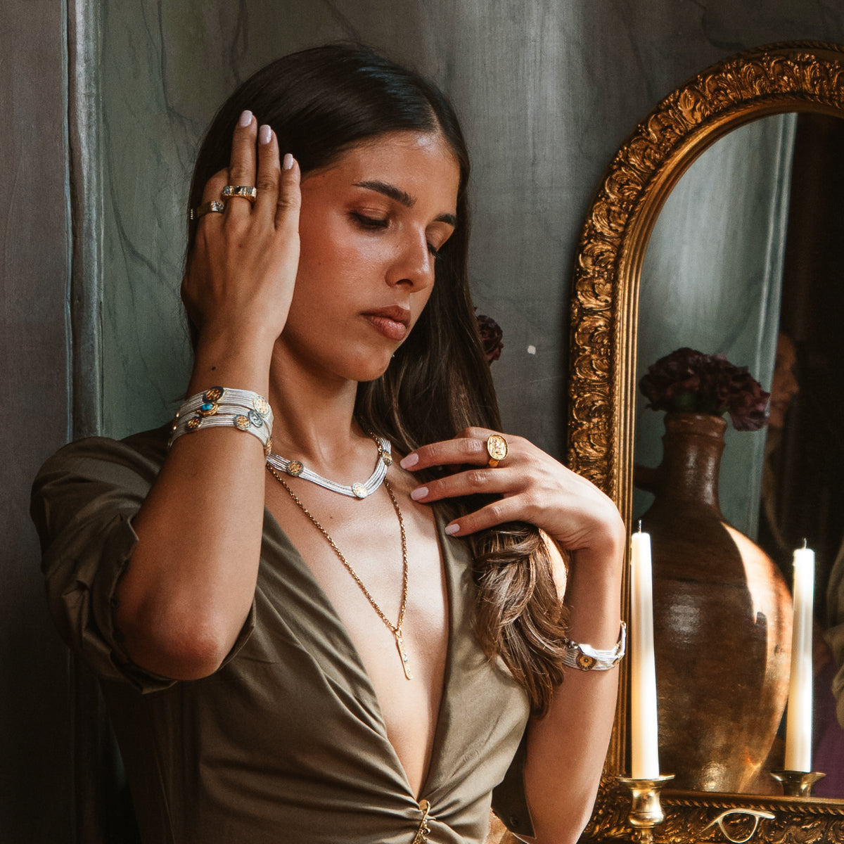 Model beside a gilded mirror wearing the Cleopatra Mystic necklace layered with a gold pendant chain