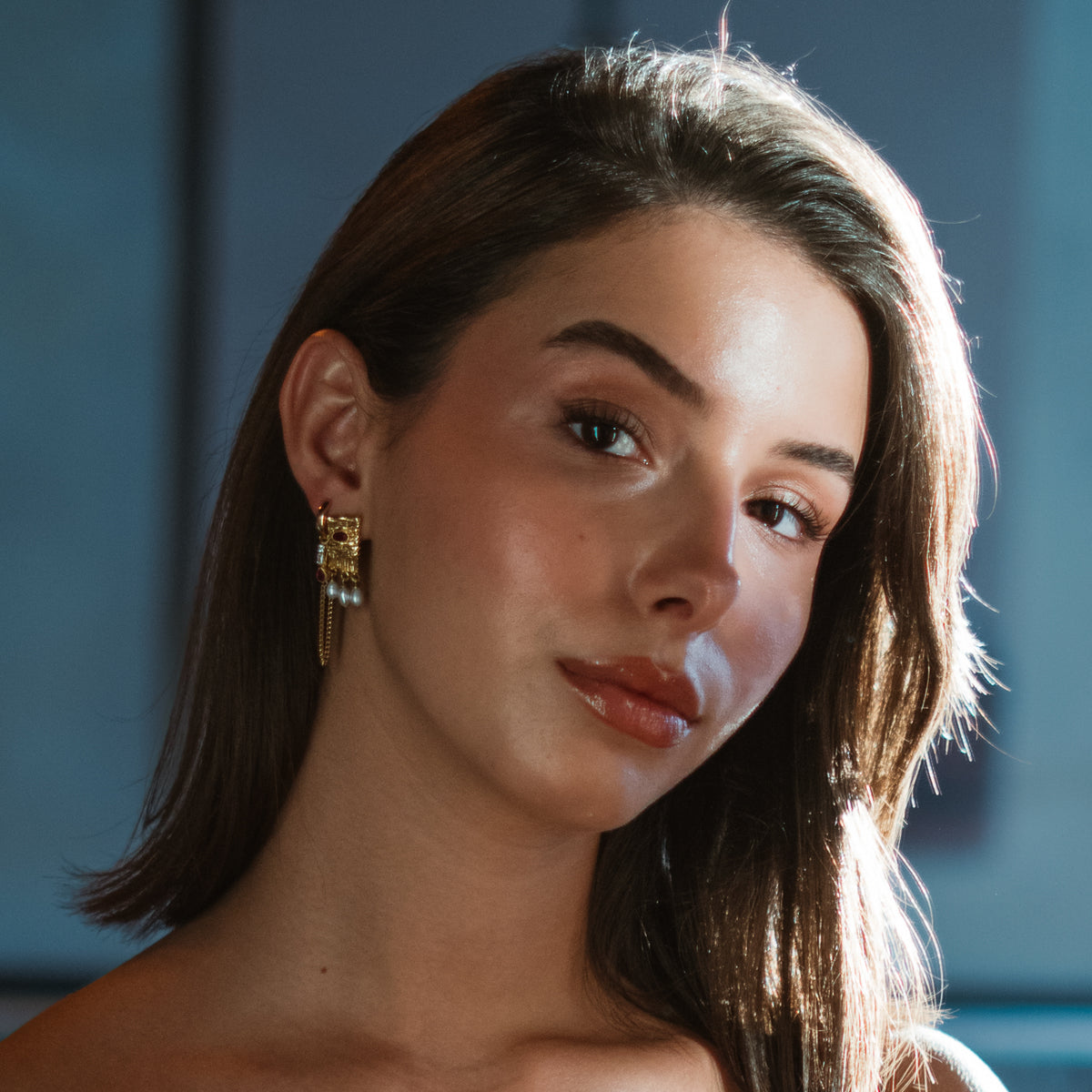 Model with shoulder length hair wearing the Cleopatra Ruby & Pearl gold statement earrings