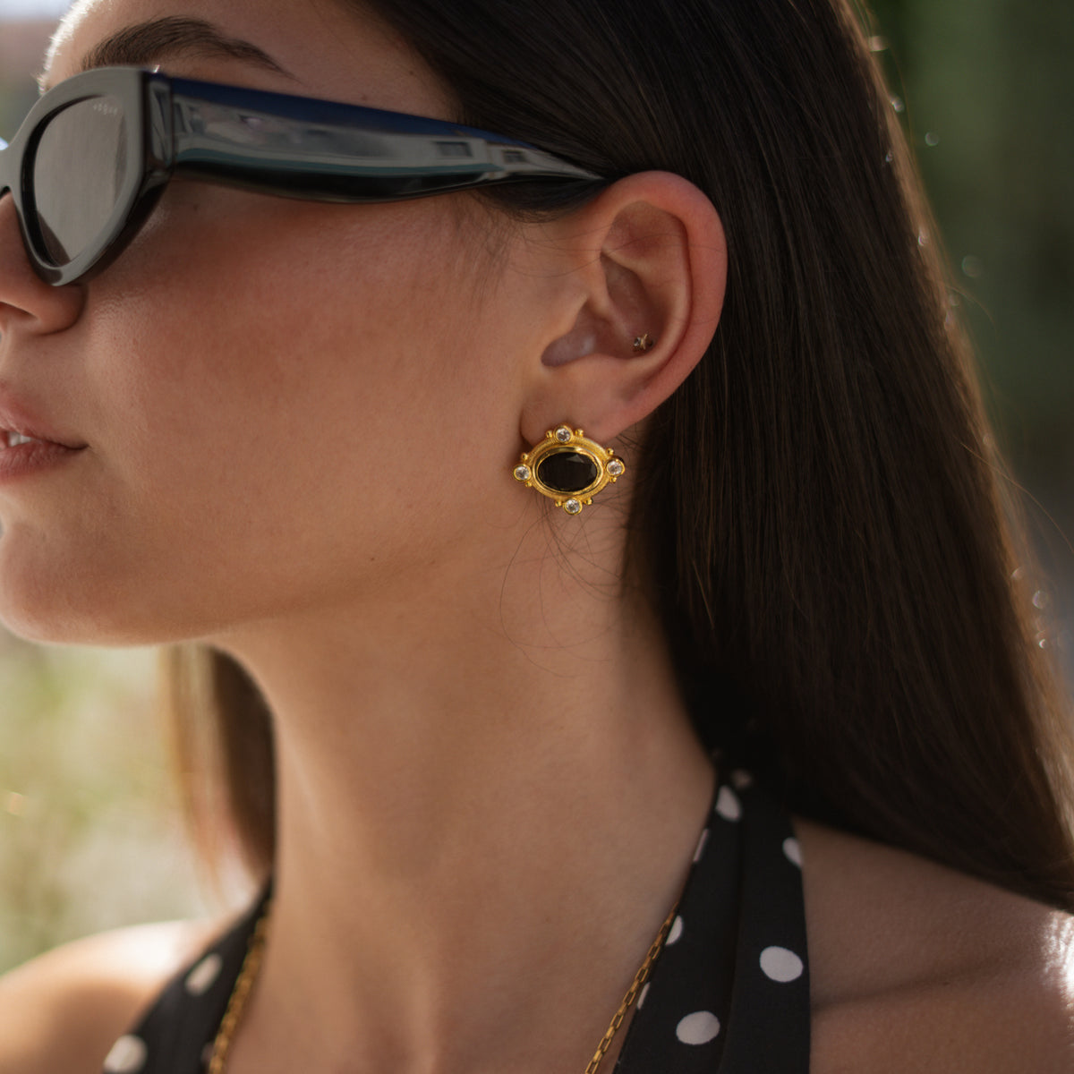 Close view of a model's ear wearing a Cleopatra black cat's eye gold stud earring