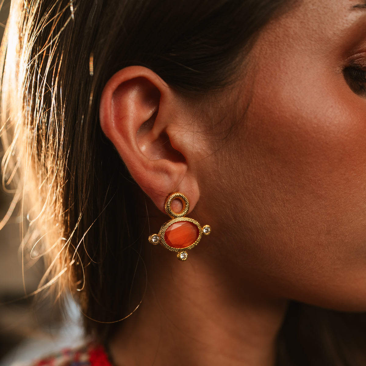 Model wearing the Cleopatra Sun Cat Eye Gold Statement Earrings, an orange cat eye stone below an open beaded gold ring