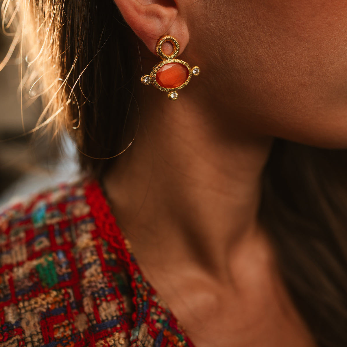 Cleopatra Sun Cat Eye Gold Statement Earring on the model, worn with a red woven top