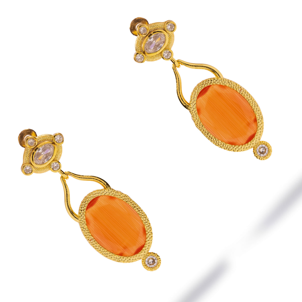 Cleopatra Sunset Cat Eye Gold Drop Earrings laid diagonally on white, orange cat eye stones with clear zircon accents