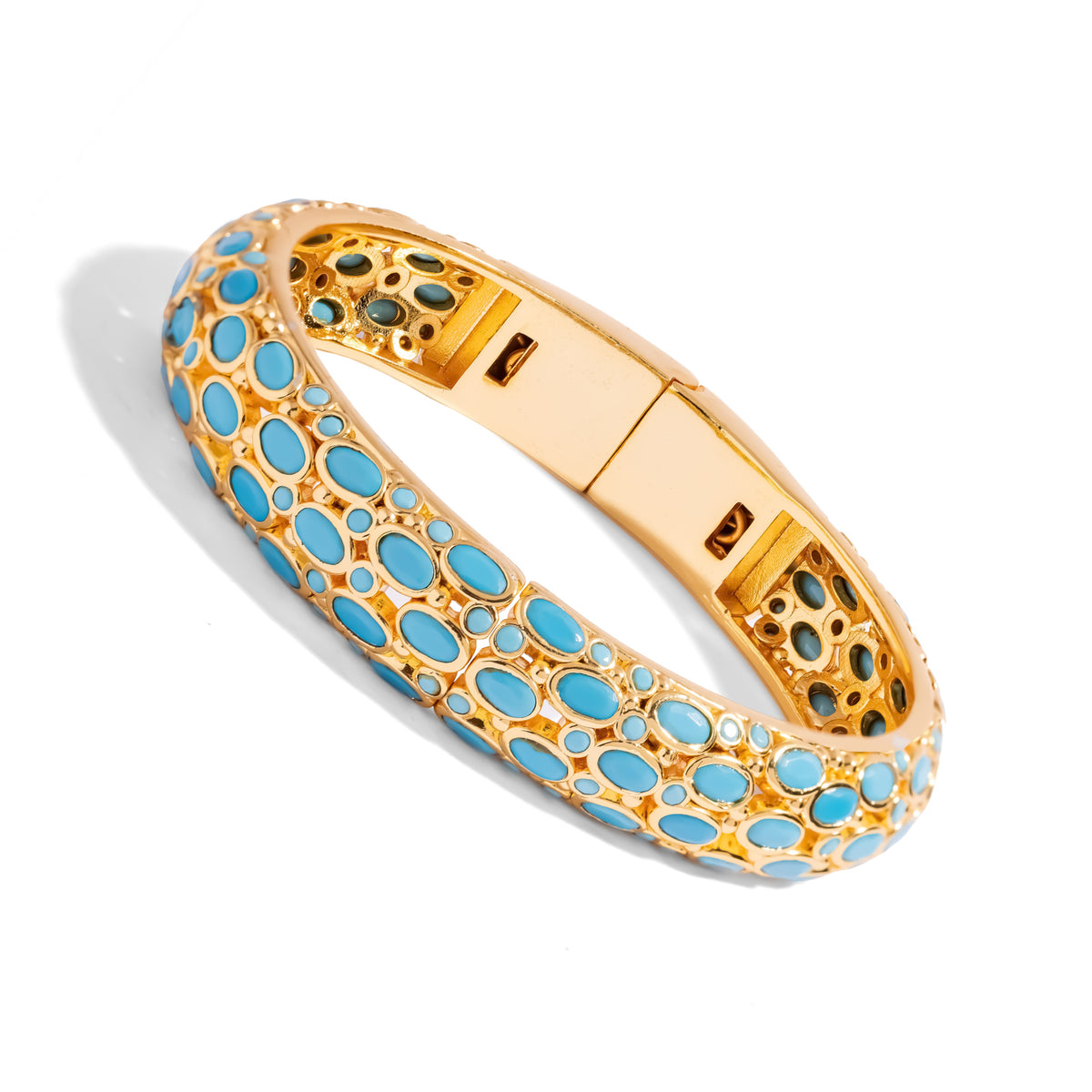 Angled view of the hinged turquoise gold bangle showing the clasp and the stone pattern