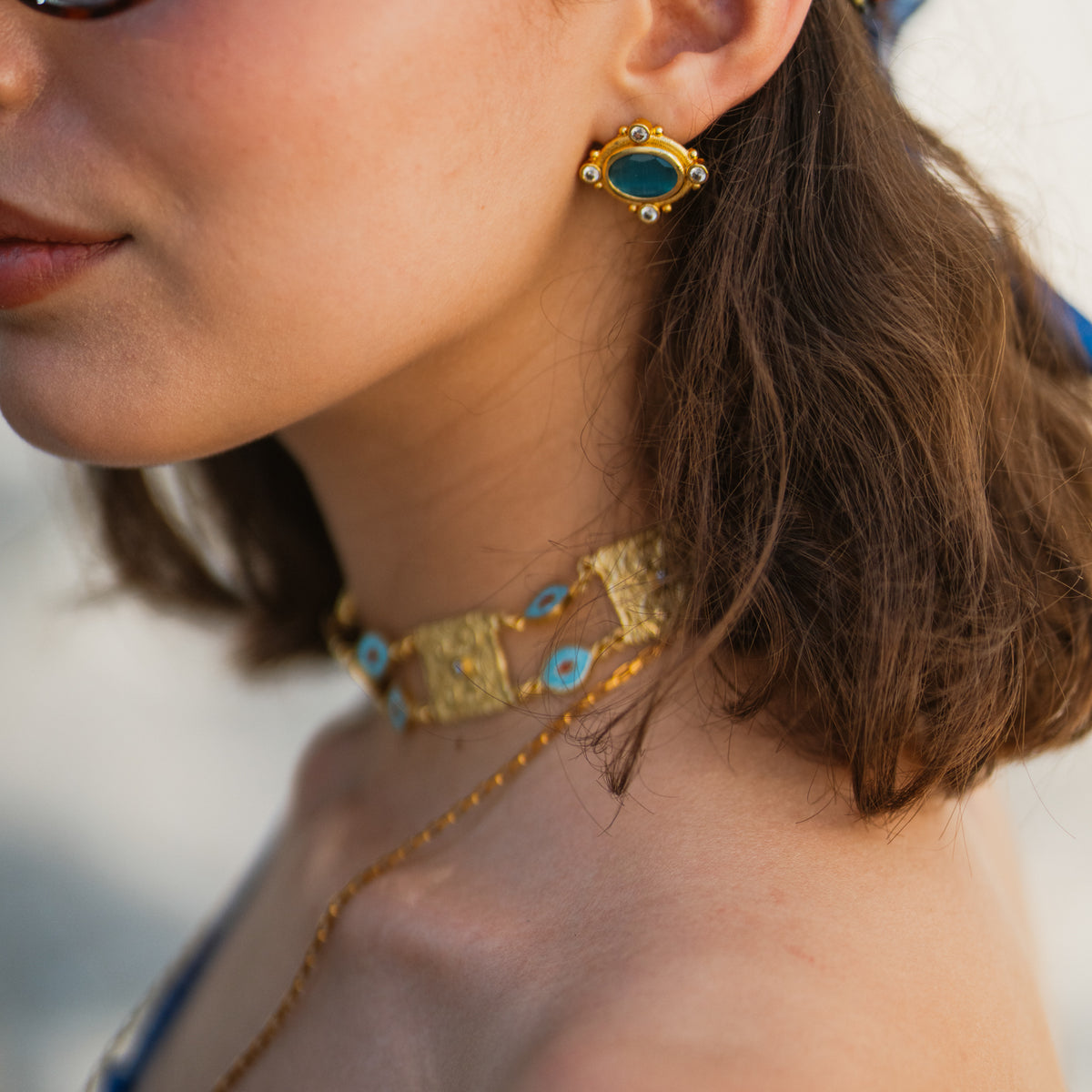Close view of the Cleopatra Turquoise stud on the ear, the cat eye stone reading deep blue-green in daylight