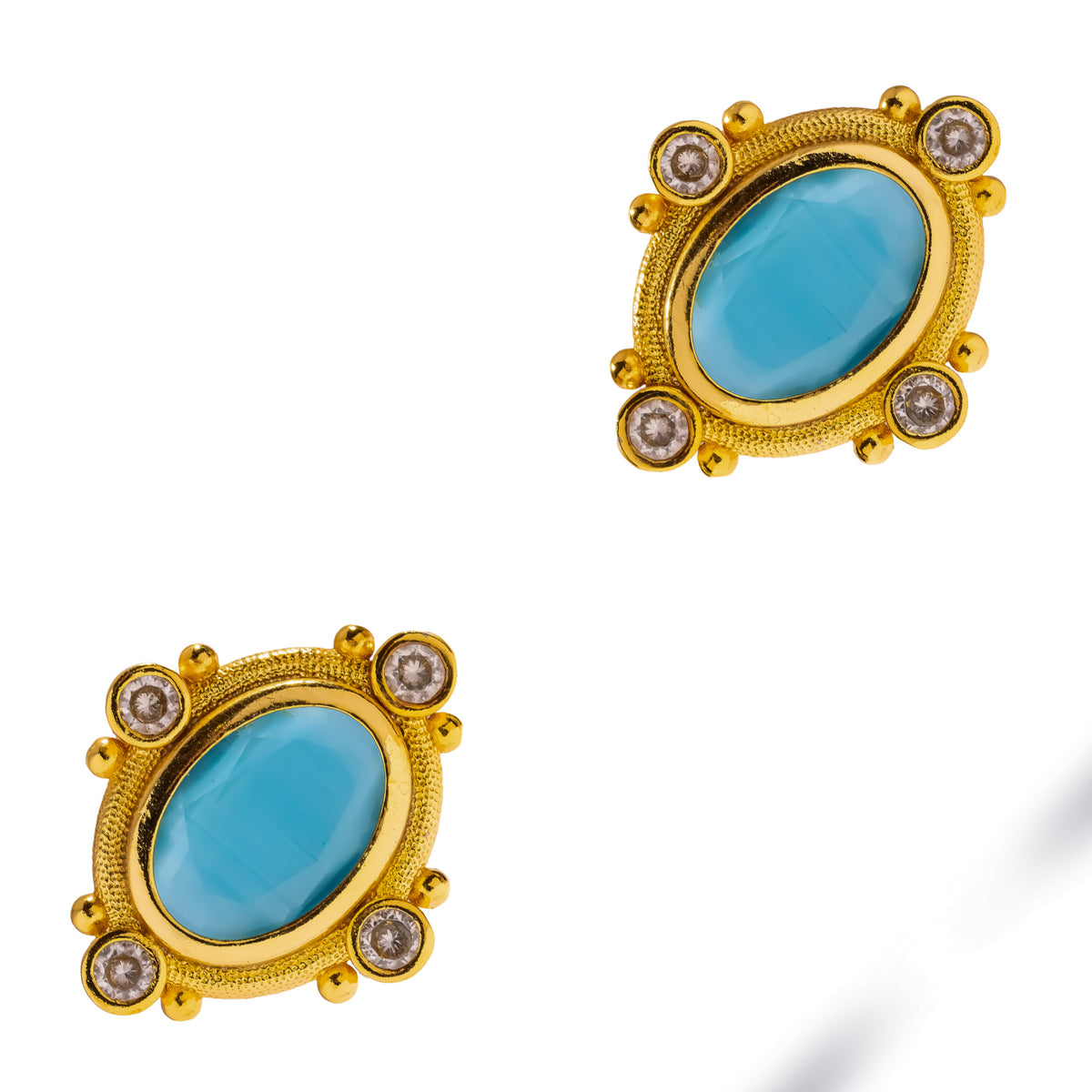 Cleopatra Turquoise Cat Eye Gold Statement Stud Earrings laid diagonally on white, granulated gold frames and clear accents