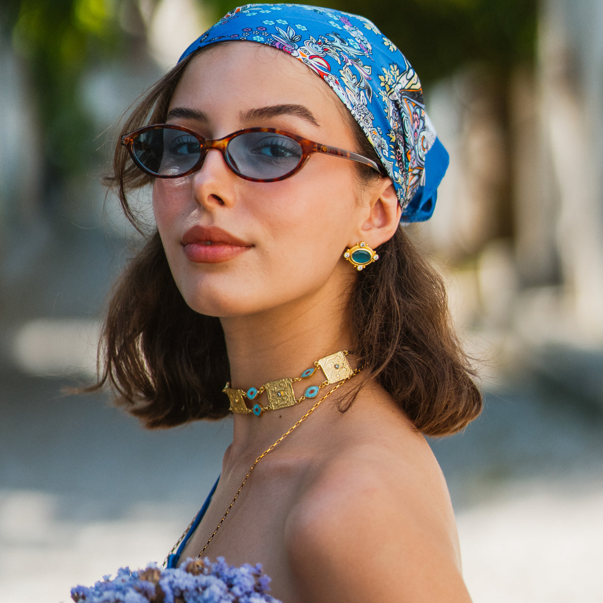 Model in a blue paisley headscarf and tortoiseshell sunglasses wearing the Cleopatra Turquoise cat eye gold stud earring