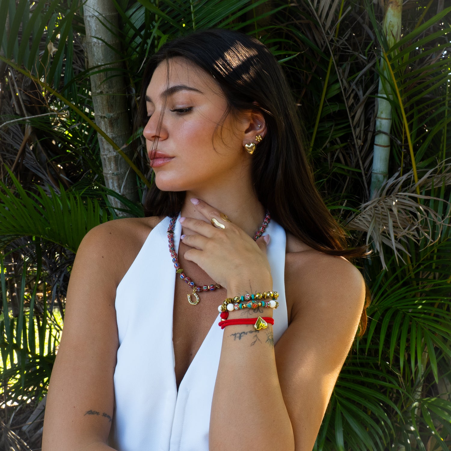 Woman wearing handmade Coastal Bohemia bracelet set with white jade, turquoise and gold hematite beads paired with a boho beaded necklace