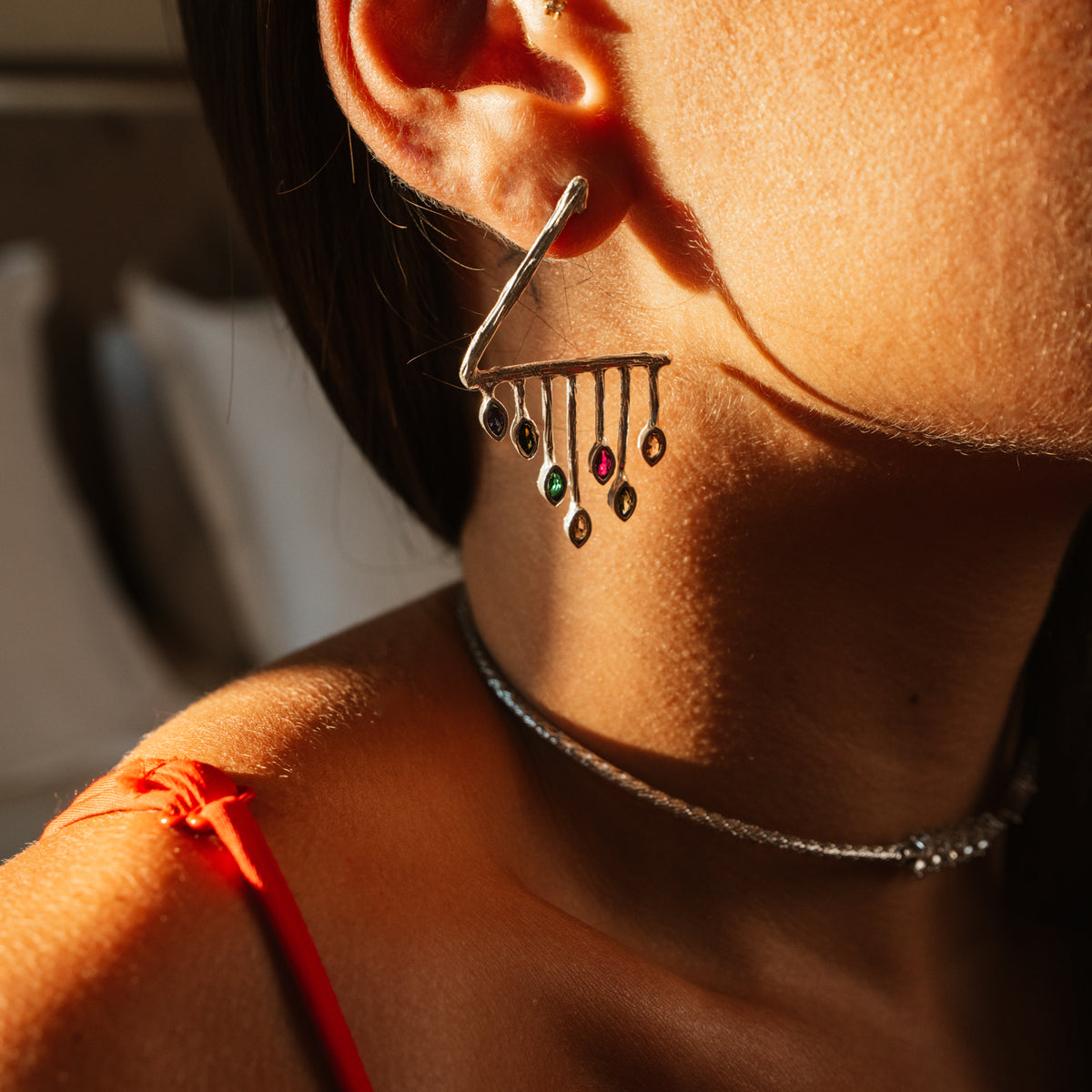 Color Rhythm silver earring worn in warm light, multicolor marquise stones hanging below the ear