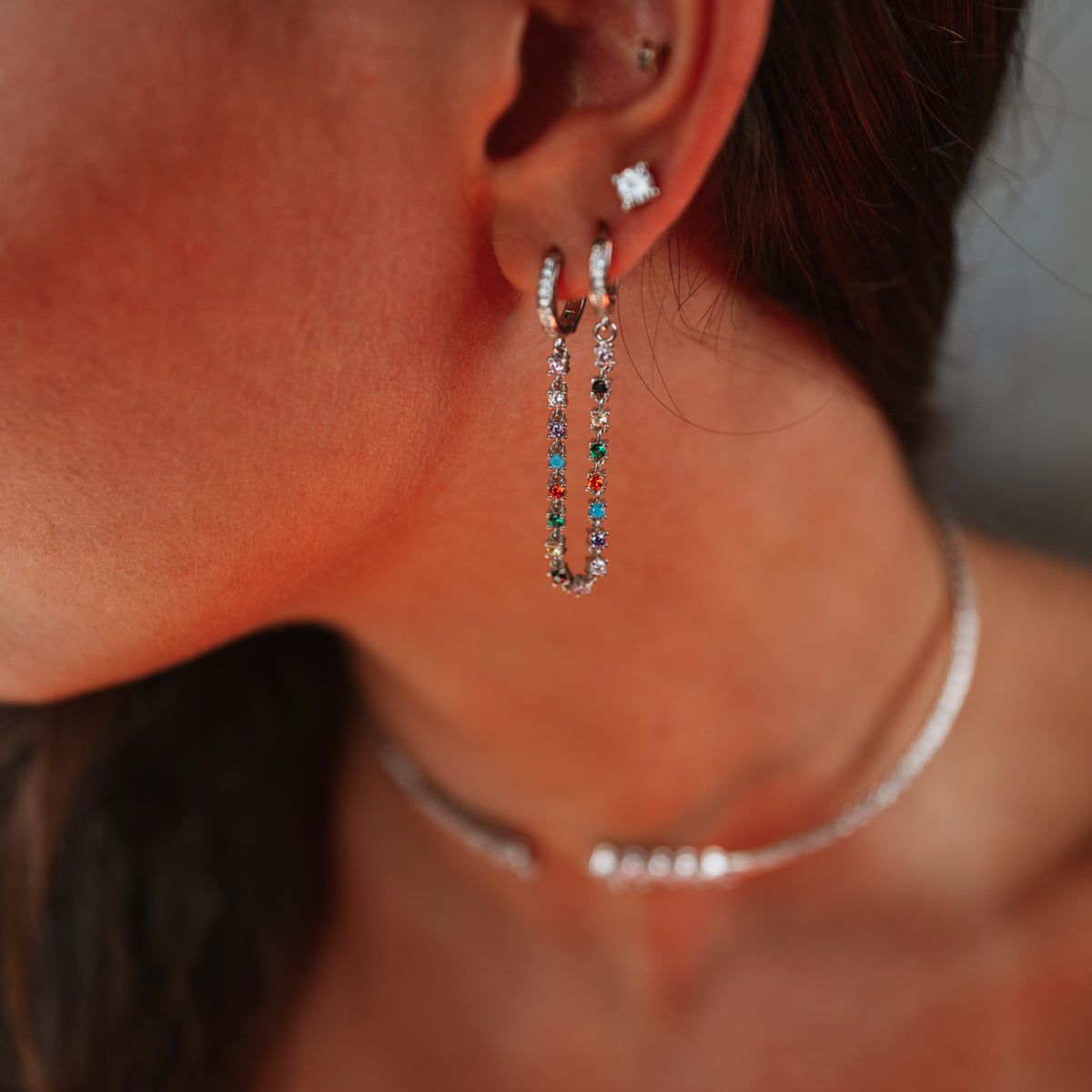 Color Story earrings worn as an ear stack, connected pave hoops in the lobe and the solitaire stud above