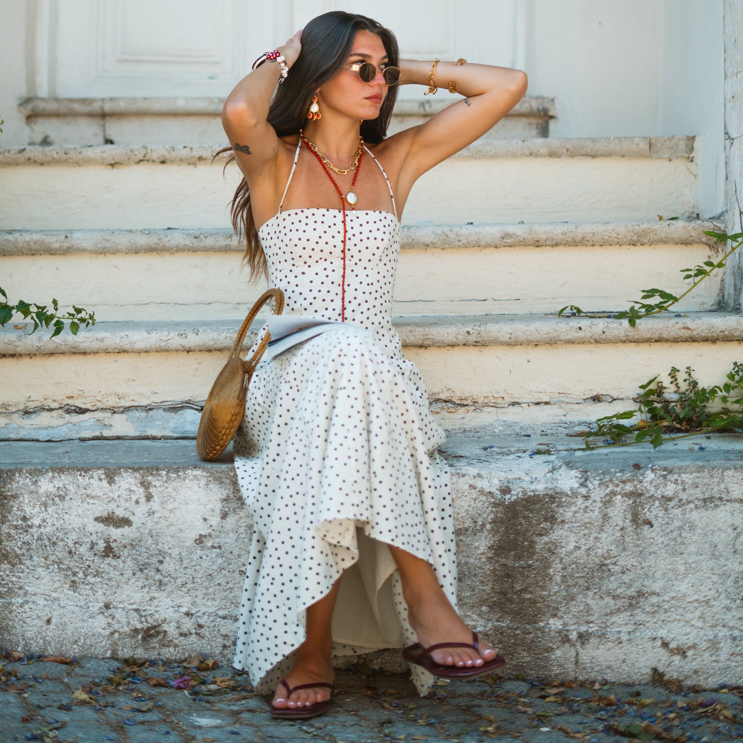 Full length view of the coral pearl lariat necklace worn with a boho polka dot dress and straw bag