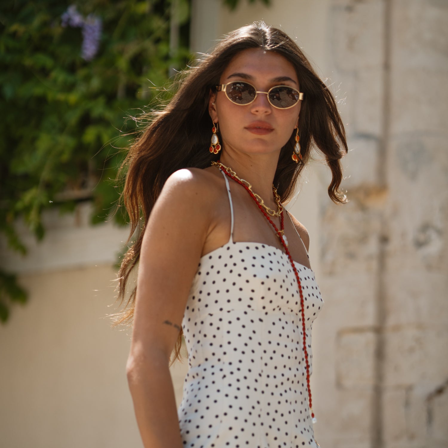 Close-up of the coral beaded lariat necklace worn close to the collarbone, paired with coral pearl drop earrings