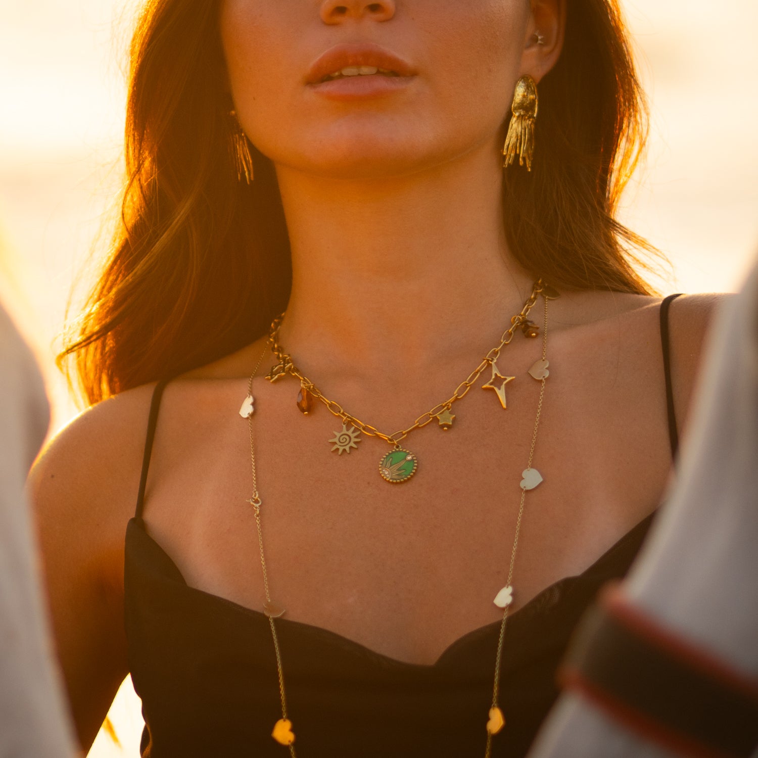 Sun, star, and green enamel charms on gold necklace representing positive energy