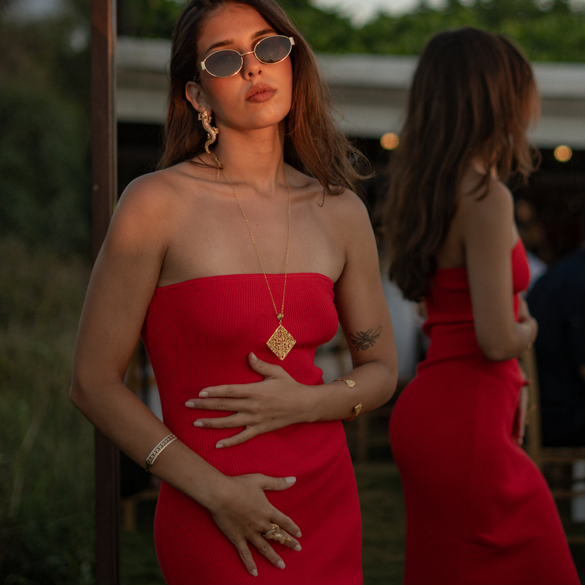Model in a red dress wearing the Crocodile Pave Zircon Gold Statement Earrings outdoors at golden hour