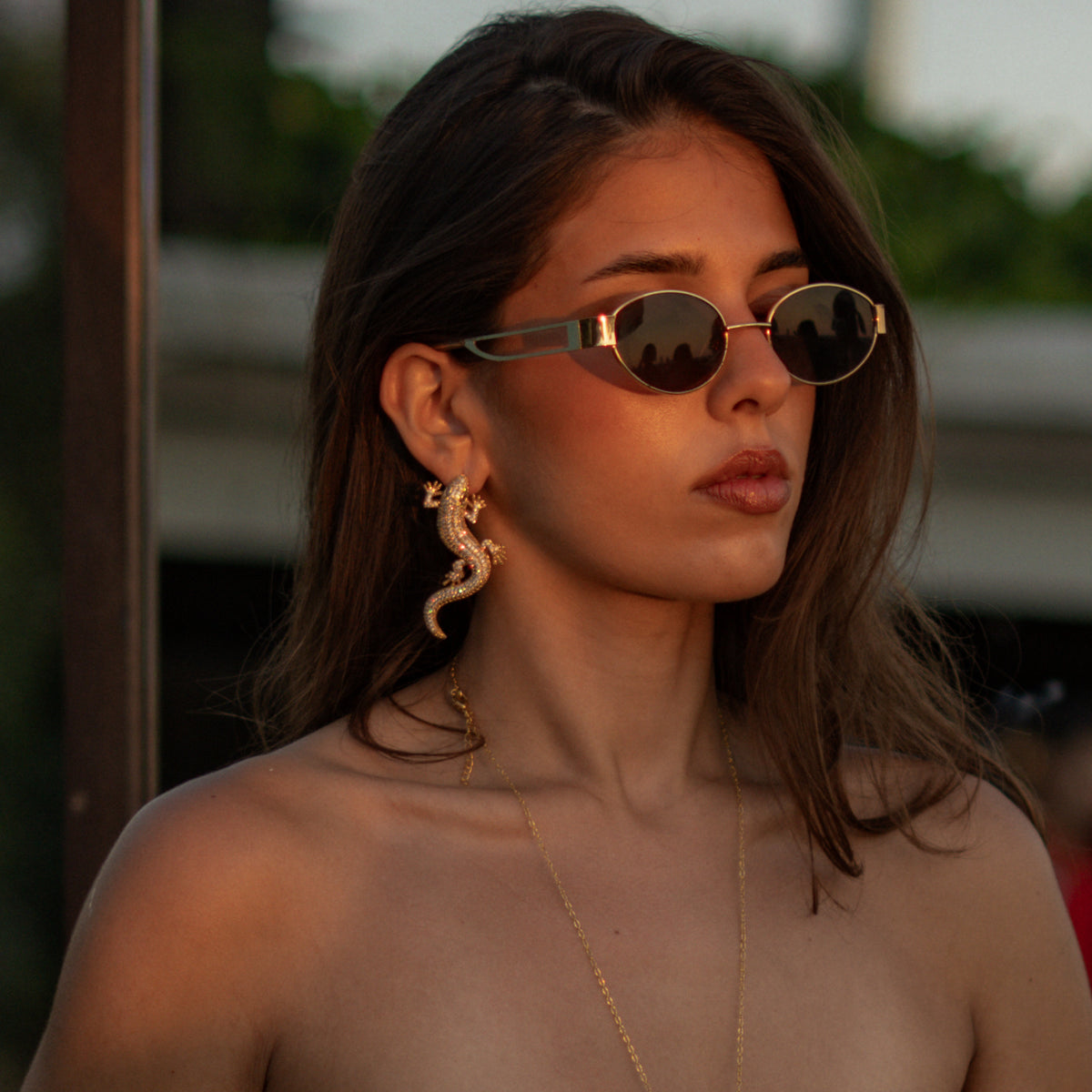 Woman in sunglasses wearing the Crocodile Pave Zircon Gold Statement Earrings, side view along the ear