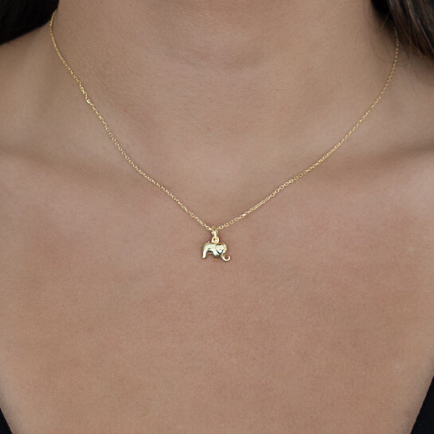 A model wearing the Dainty Gold Elephant Necklace, showcasing its grace and elegance as it rests delicately against their collarbone.