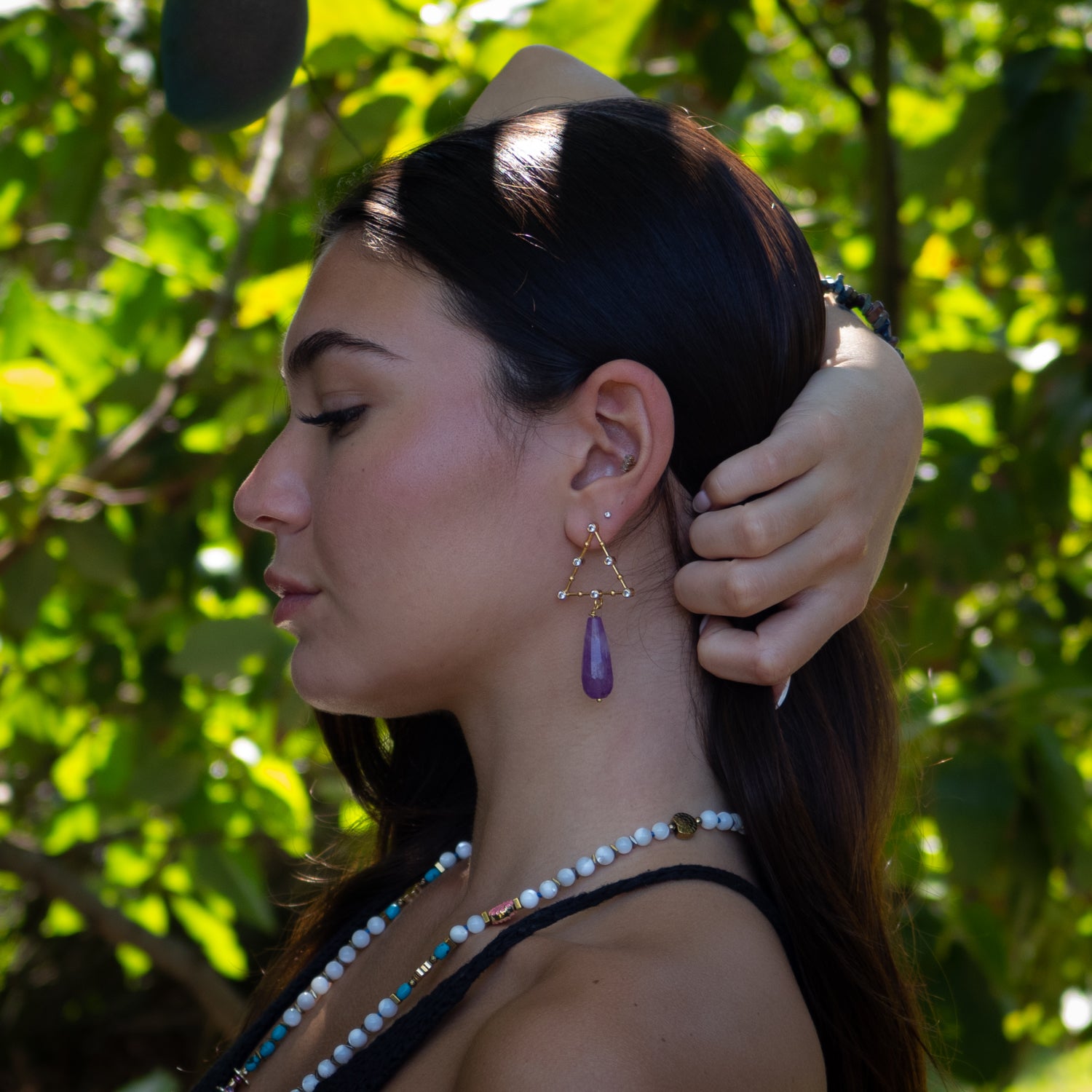 Close-up of triangle-shaped CZ diamond earrings with radiant purple amethyst drops

