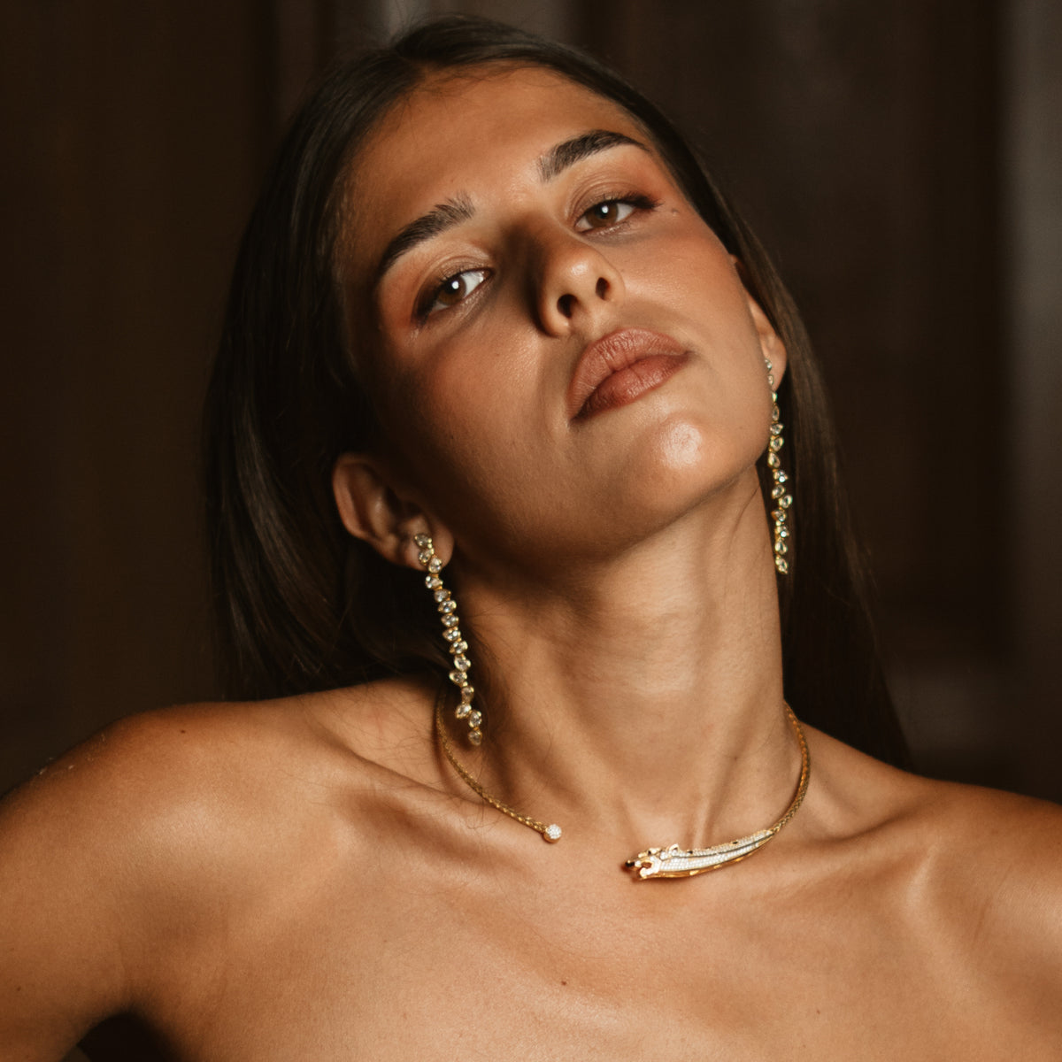 Woman with her head tilted back wearing the elegant long vine earrings in 24K gold plated brass