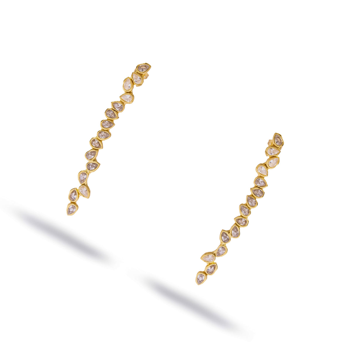 Pair of long gold drop earrings with pear cut white zircon leaves, angled view on white