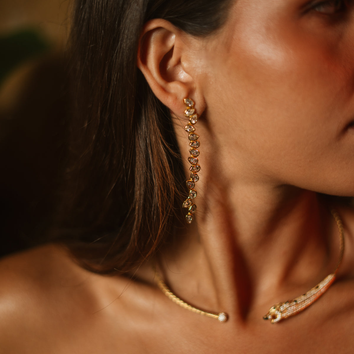 Close view of the white zircon vine drop earring at the ear above a pavé panther collar necklace