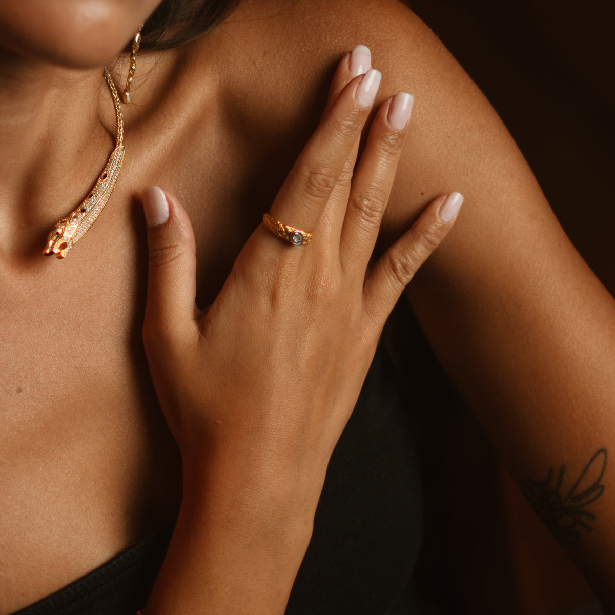 Model in low light wearing the Antique Ember rose cut band ring with a gold collar necklace