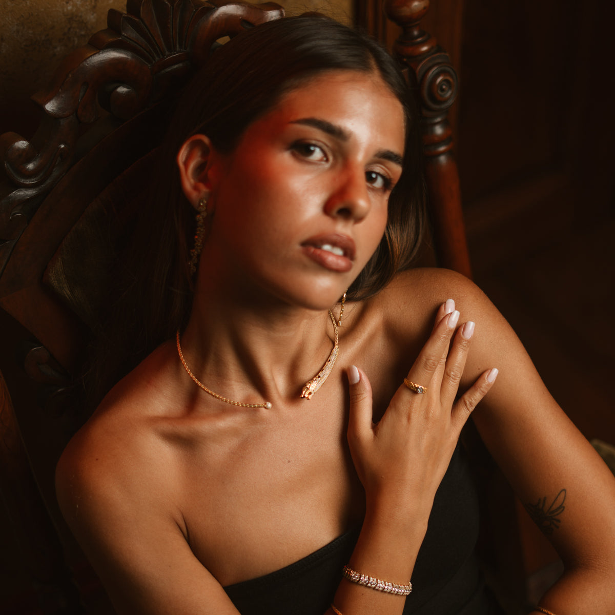 Model seated in an antique carved chair wearing the Antique Ember rose cut gold band ring