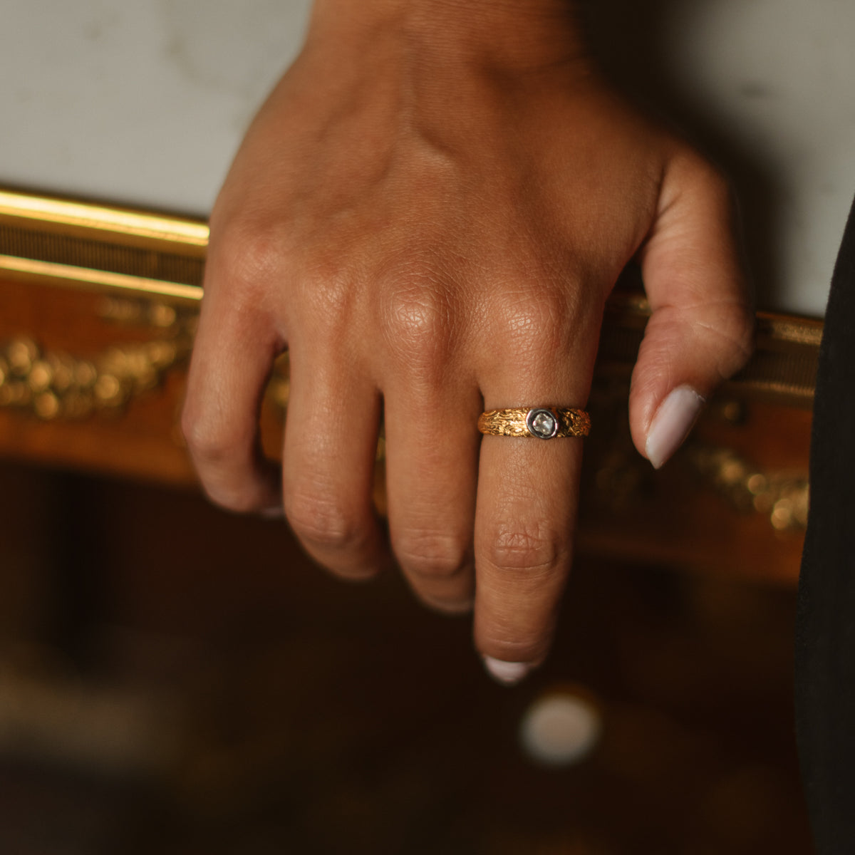 Close up of the Antique Ember band ring worn on the finger, showing its slim stackable profile