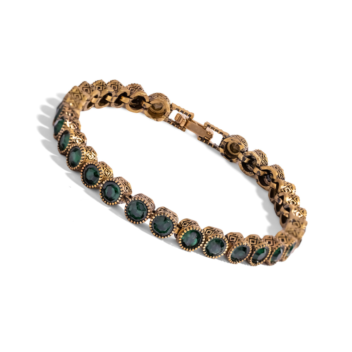 Angled studio view of the emerald tennis bracelet showing the diamond motif bezels and the beaded rim around each stone
