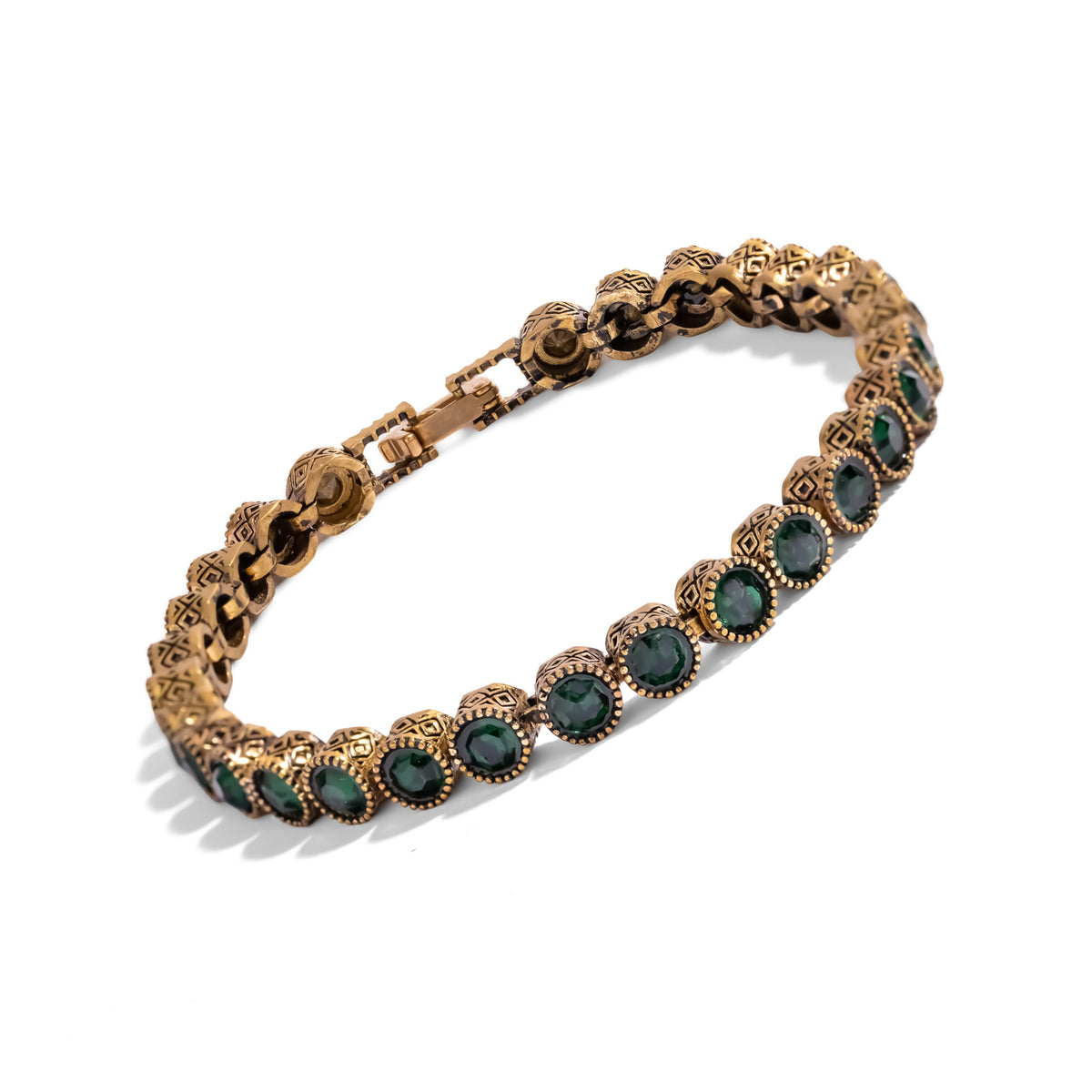 Three quarter view of the emerald antique gold tennis bracelet, the darkened finish sitting in the recesses of the pattern