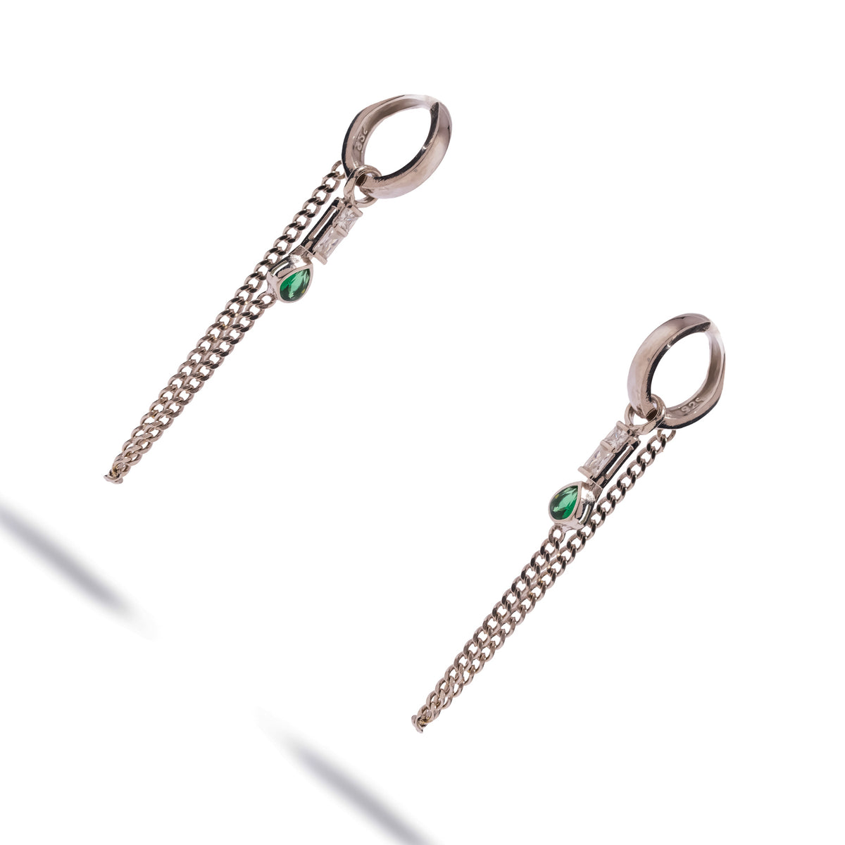 Pair of sterling silver chain drape huggie earrings shown at an angle against white
