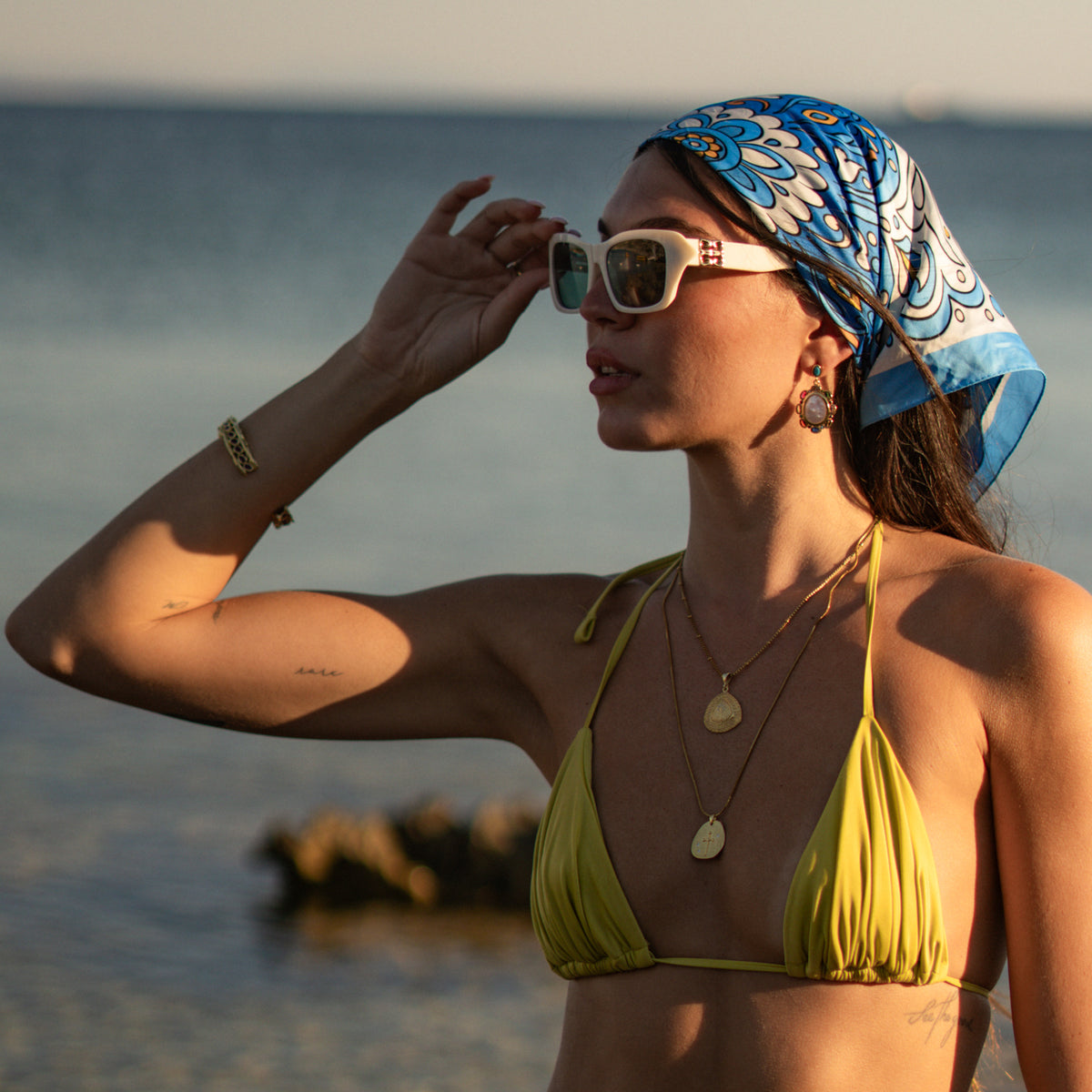 Model at the shore wearing the baroque pearl gold drop earrings with two layered gold pendant necklaces