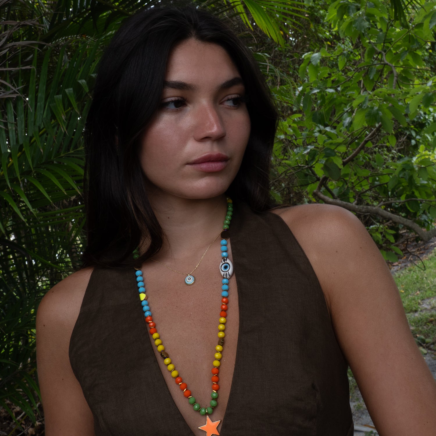Multicolor star beaded long necklace styled on model with brown linen, vacation jewelry
