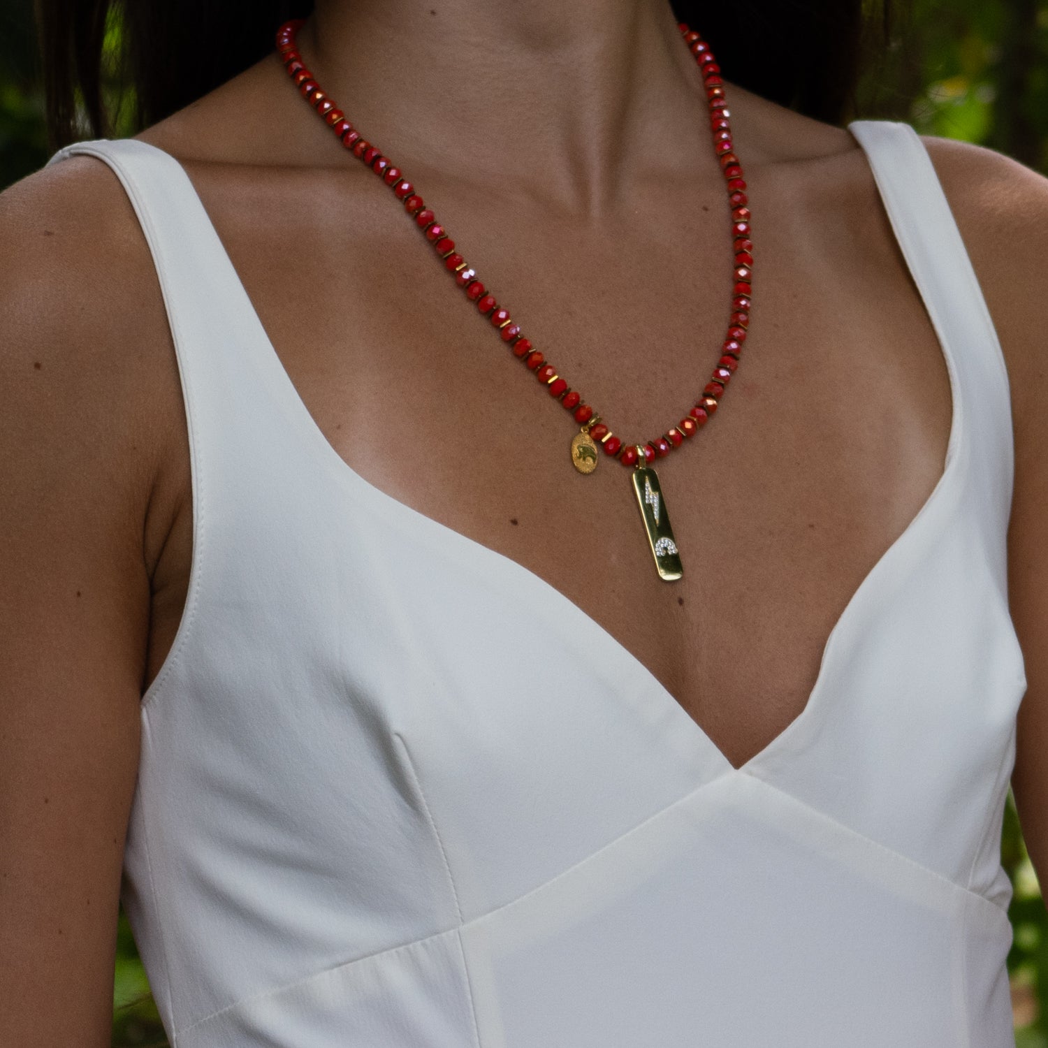 Close-up of faceted orange-red beads with gold hematite spacers and spiritual symbols.

