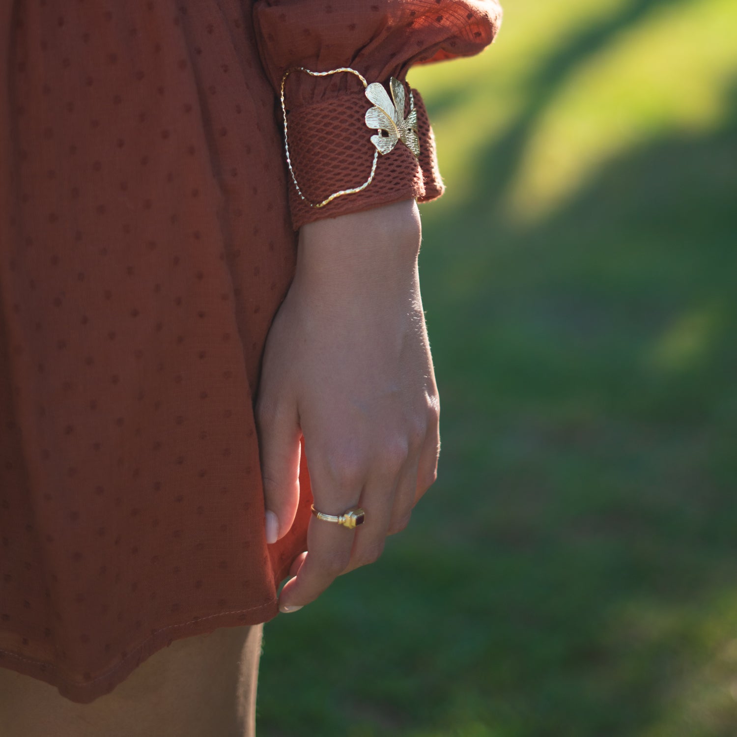 Person wearing a brown polka dot dress with a floral detail on a blurred green background